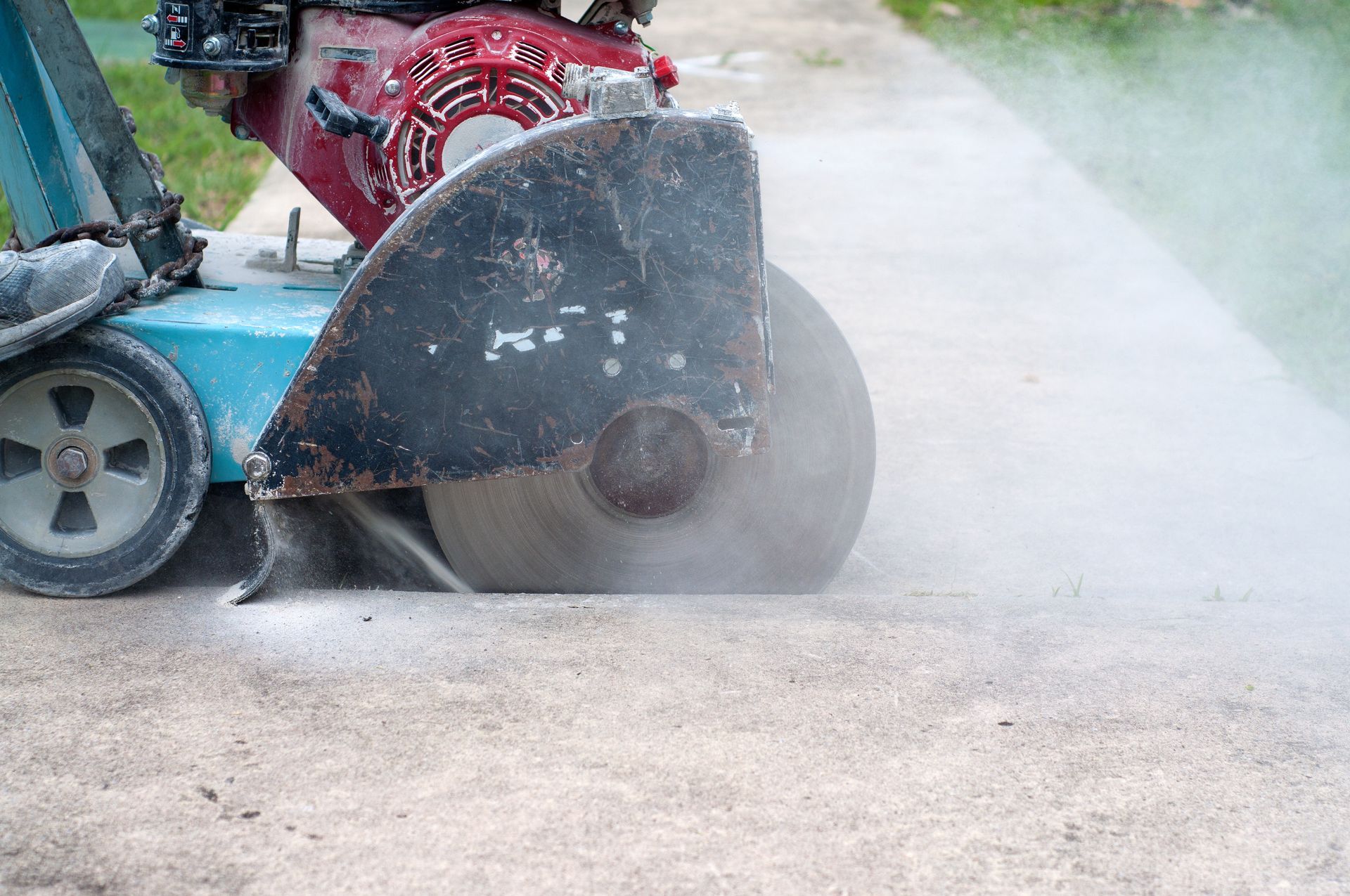 A concrete saw is cutting a concrete road.