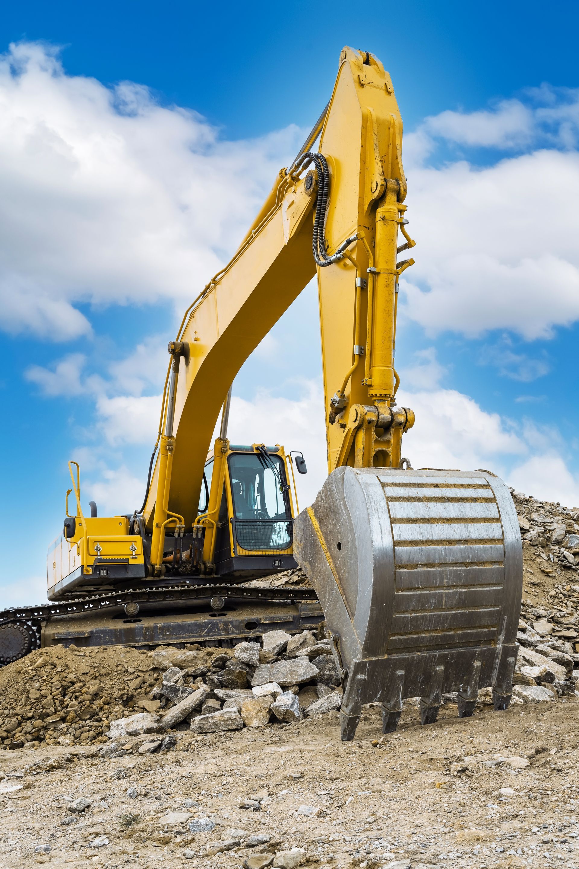 A yellow excavator is sitting on top of a pile of dirt.