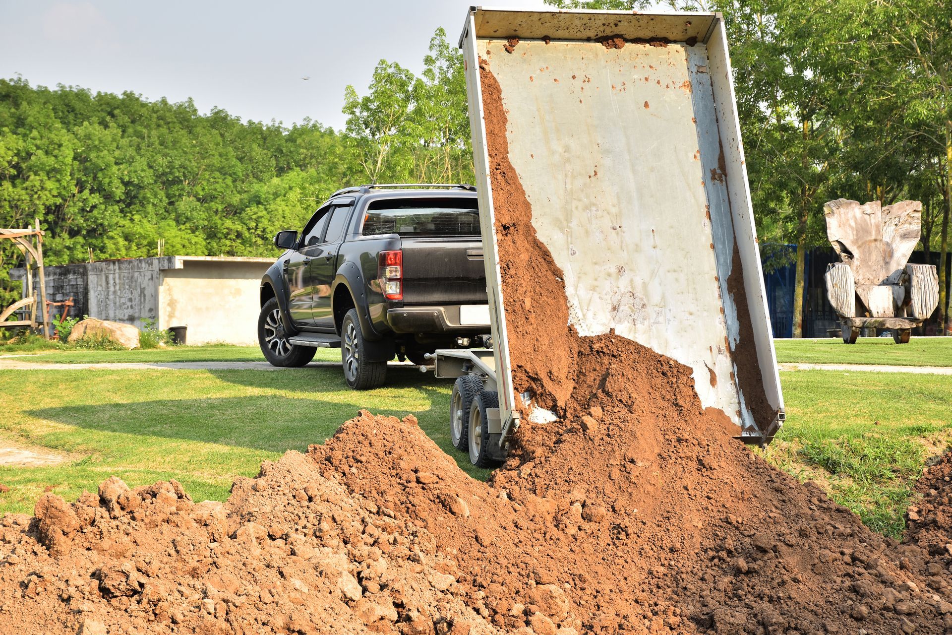 A truck is pulling a trailer full of dirt.