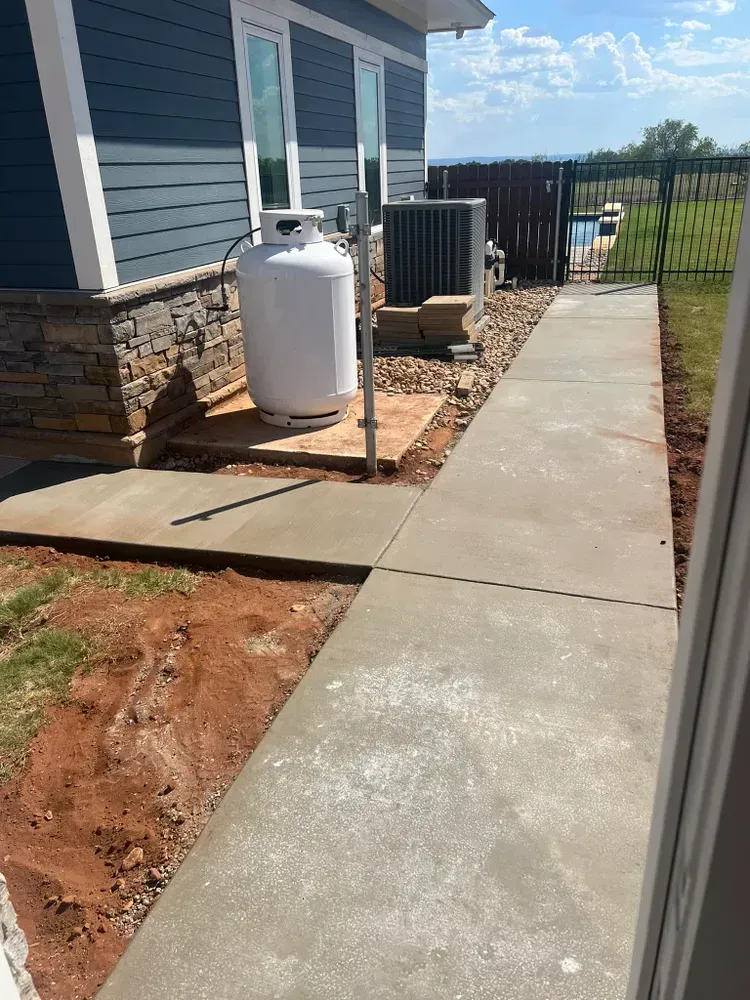 A propane tank is sitting on a sidewalk next to a house.