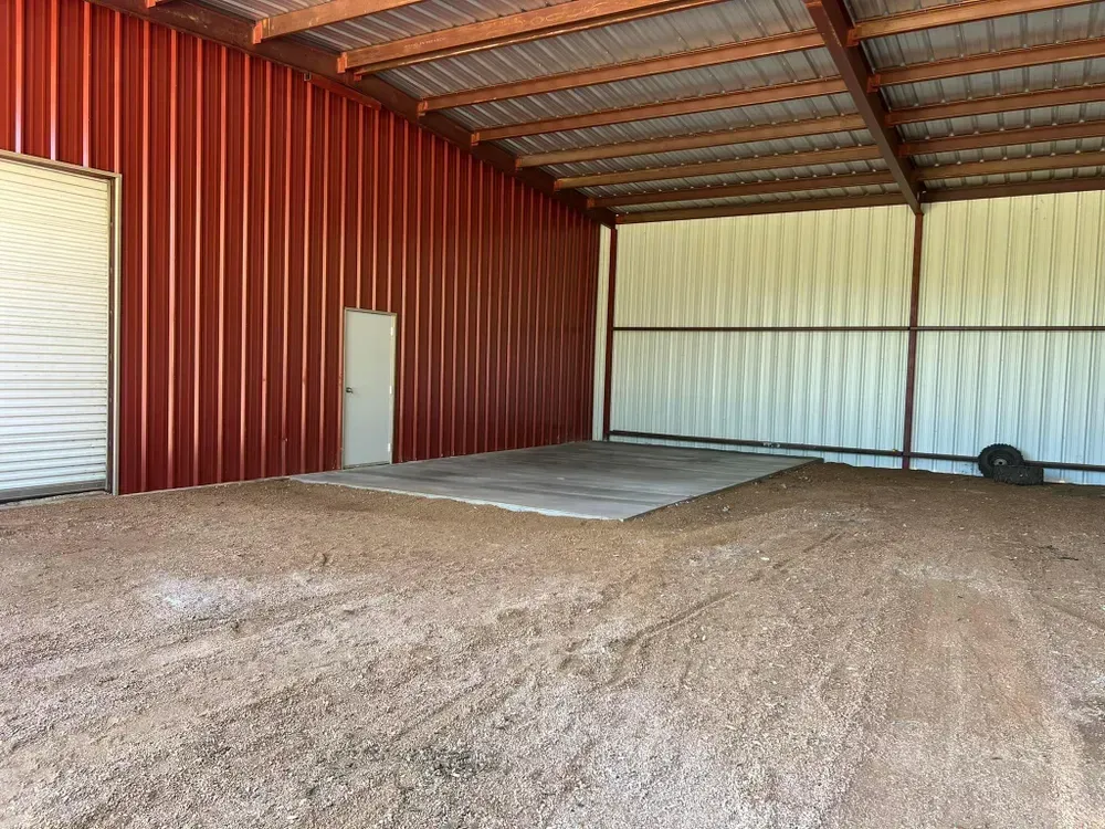 A large empty garage with a red wall and a white door.