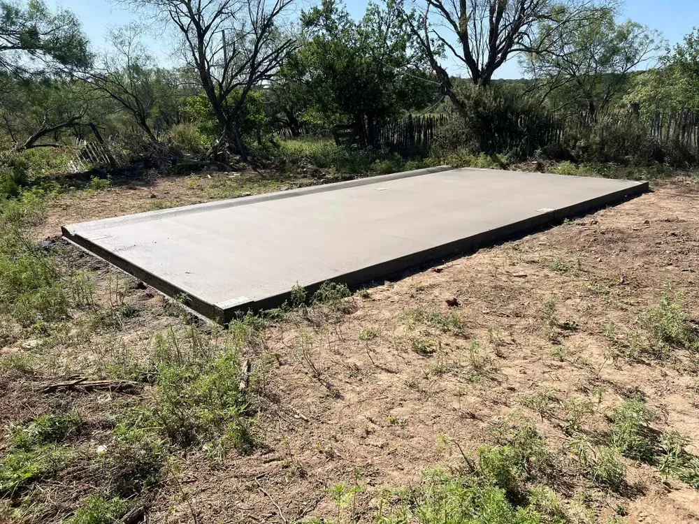 A large concrete slab is sitting in the middle of a dirt field.