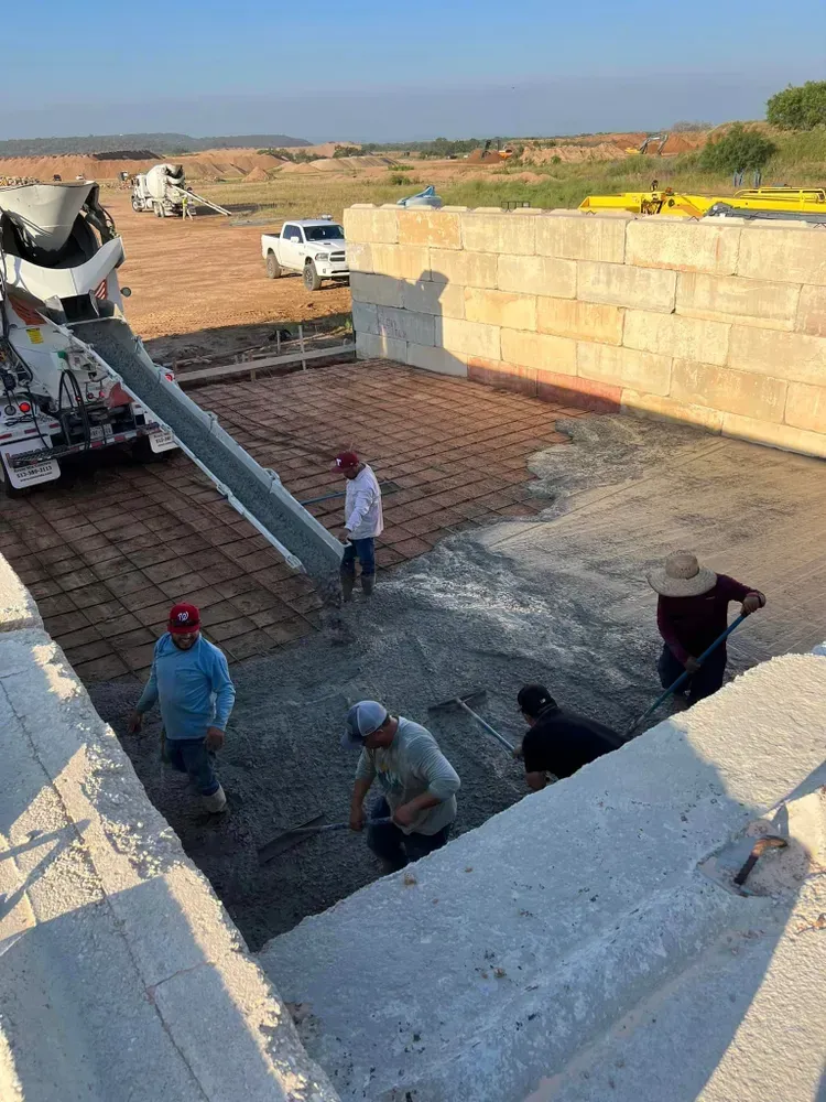 A group of construction workers are working on a concrete floor.
