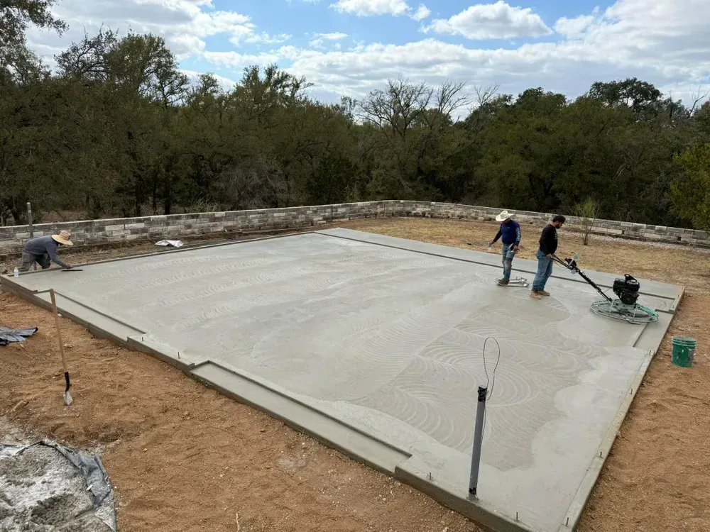 A couple of men are working on a concrete floor.