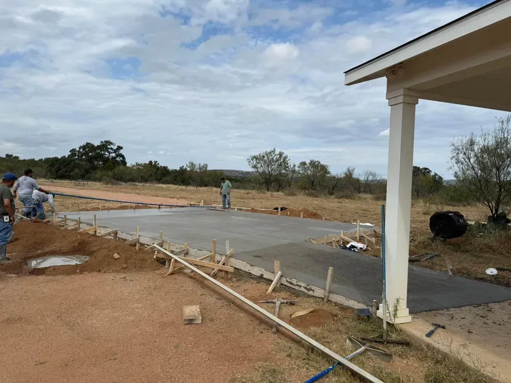 A group of construction workers are working on a concrete driveway.