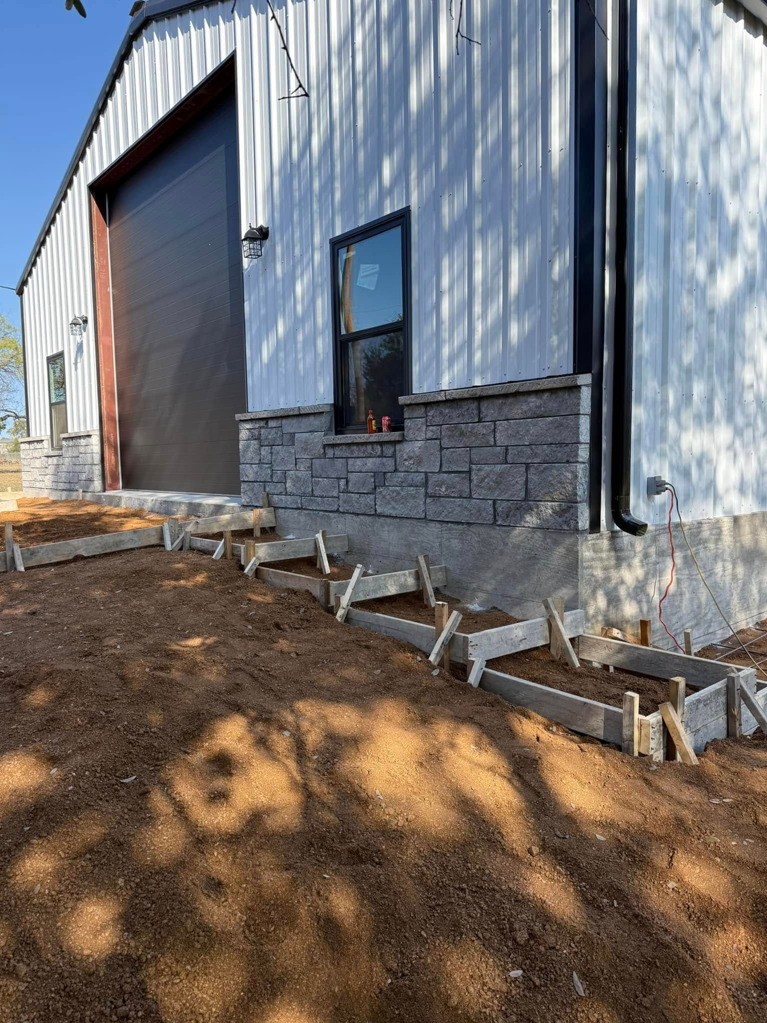 A white building with a garage door and a window is being built.