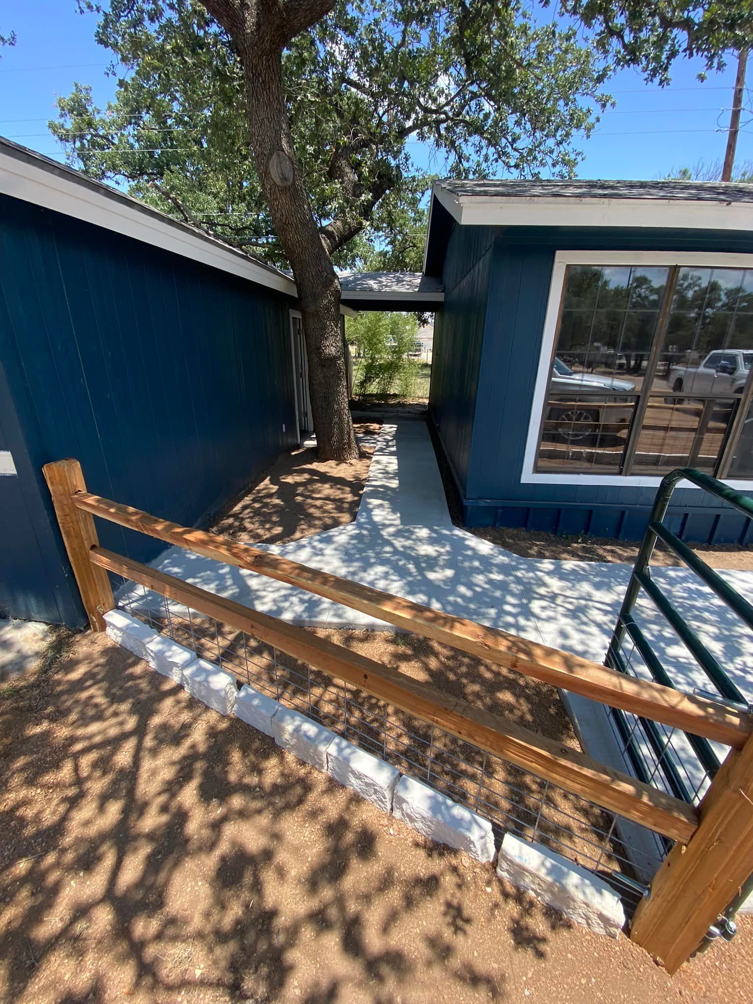 A blue house with a wooden fence and stairs leading to it.