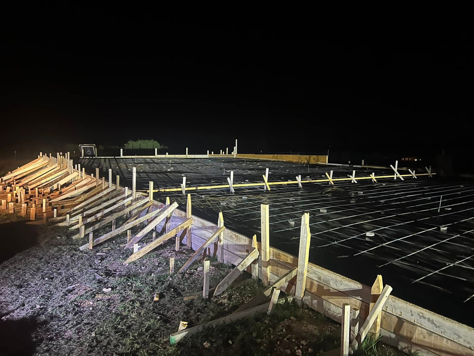 A construction site at night with a lot of wooden beams.