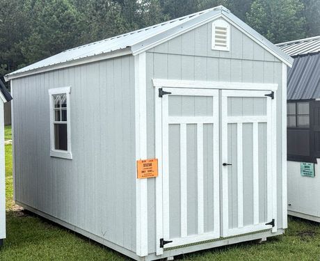 A gray and white shed with a window and doors is sitting in the grass.