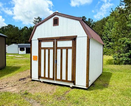 A gray and white shed with a window and doors is sitting in the grass.