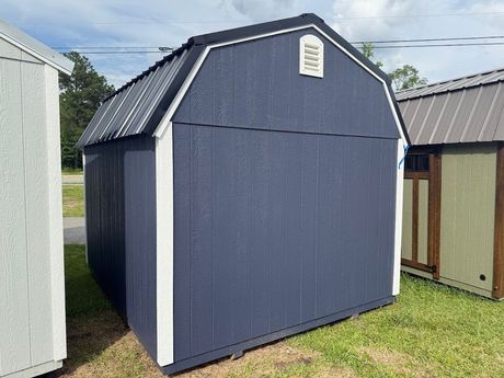 A gray and white shed with a window and doors is sitting in the grass.