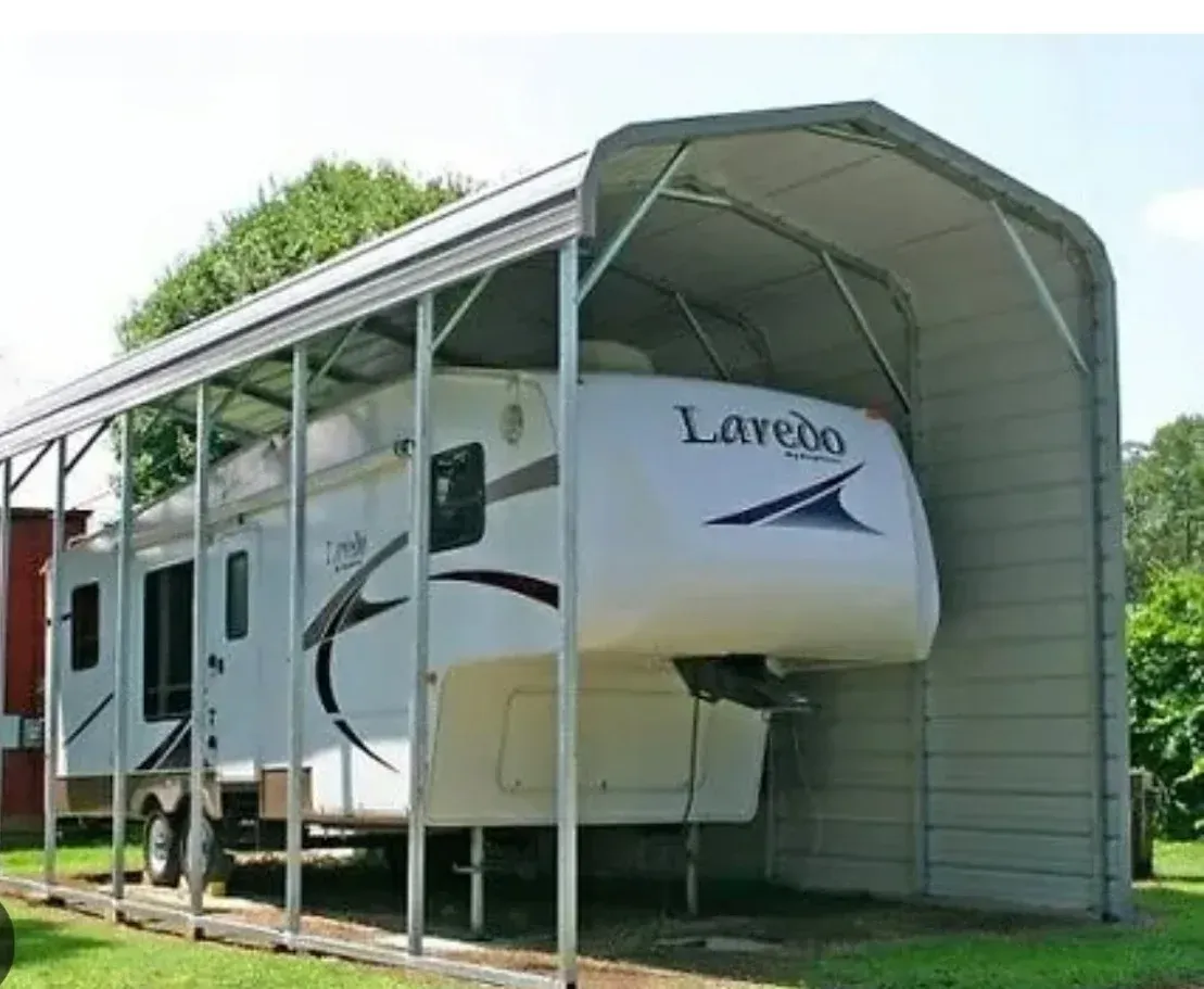 A white laredo rv is parked under a metal structure.