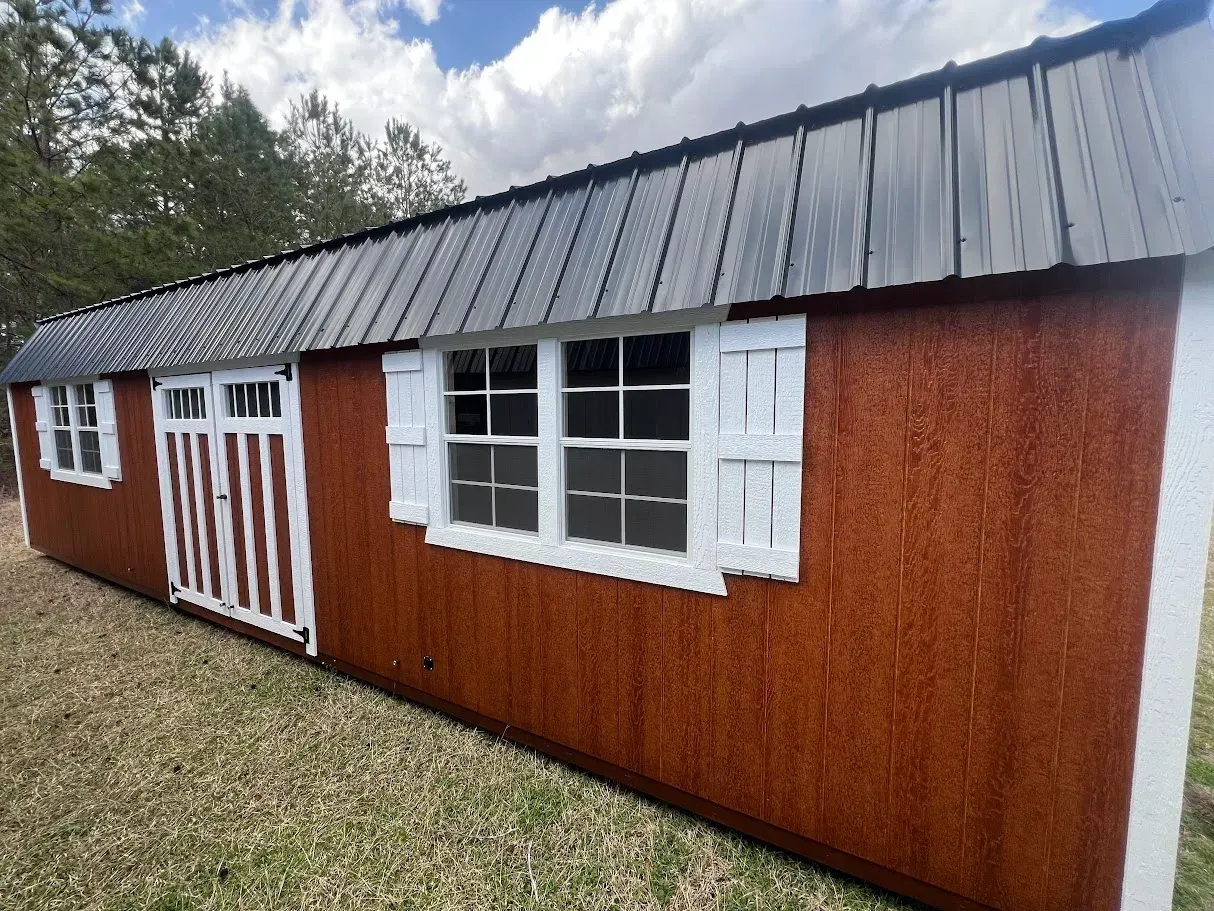 A long wooden building with a metal roof and white shutters.