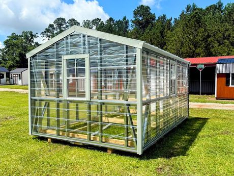 A gray and white shed with a window and doors is sitting in the grass.
