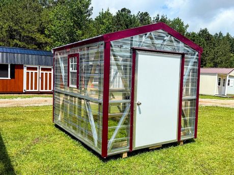 A gray and white shed with a window and doors is sitting in the grass.