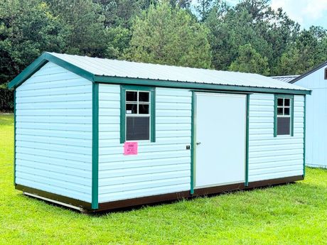 A gray and white shed with a window and doors is sitting in the grass.