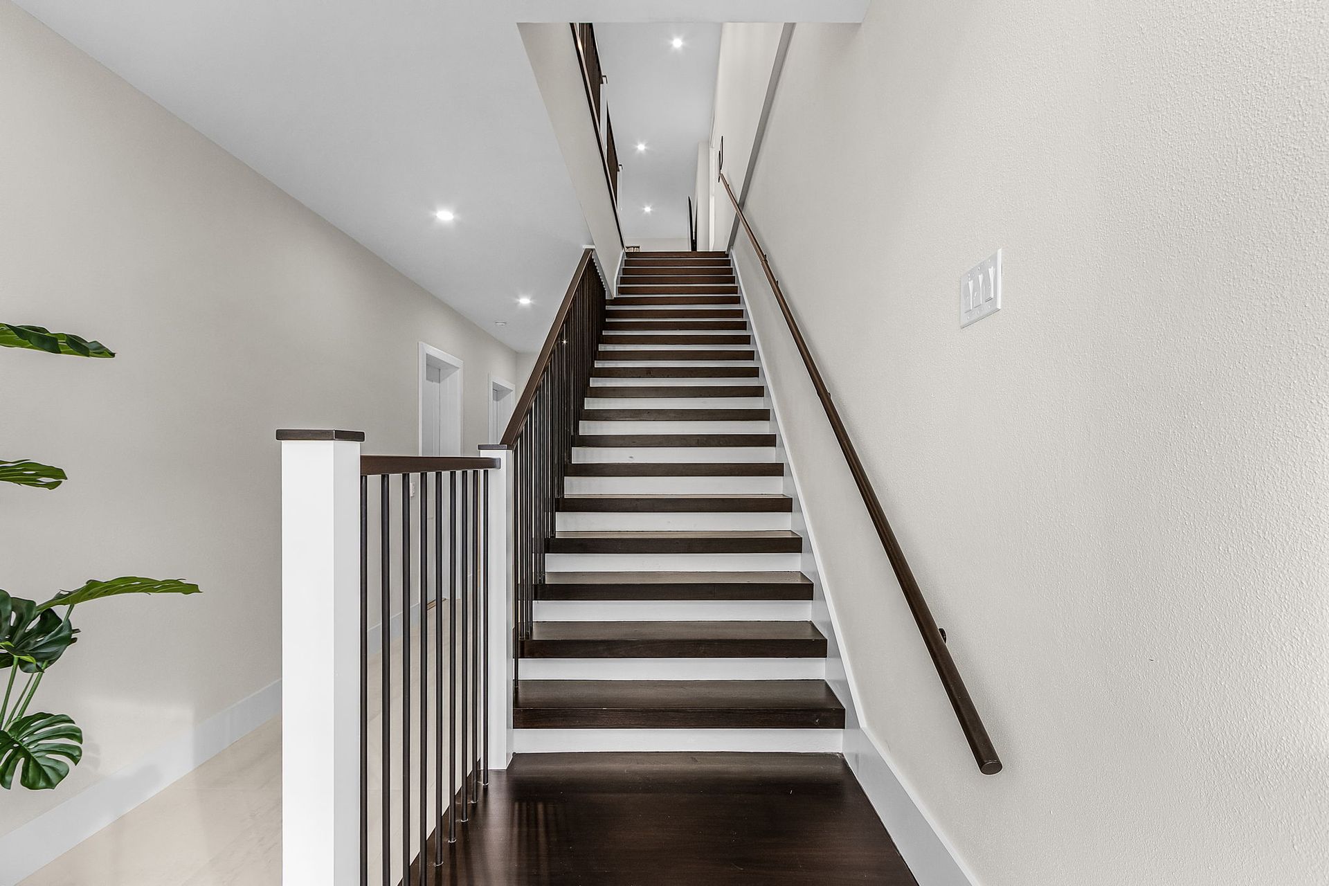 Interior staircase with dark wood treads and handrails, white walls, and bright lighting.