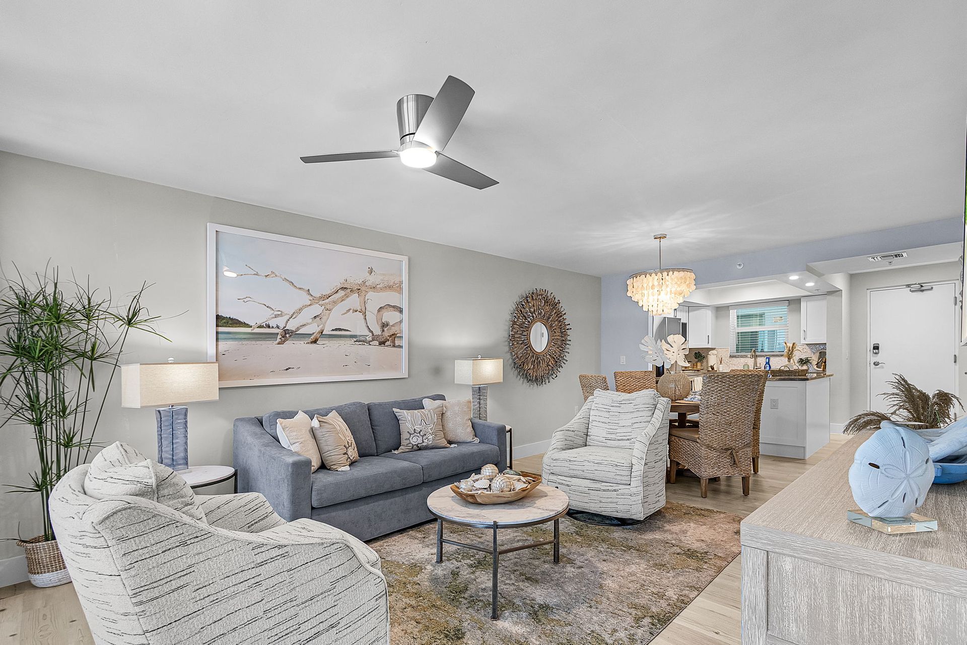 Living room with blue sofa, patterned armchairs, and dining area with chandelier.