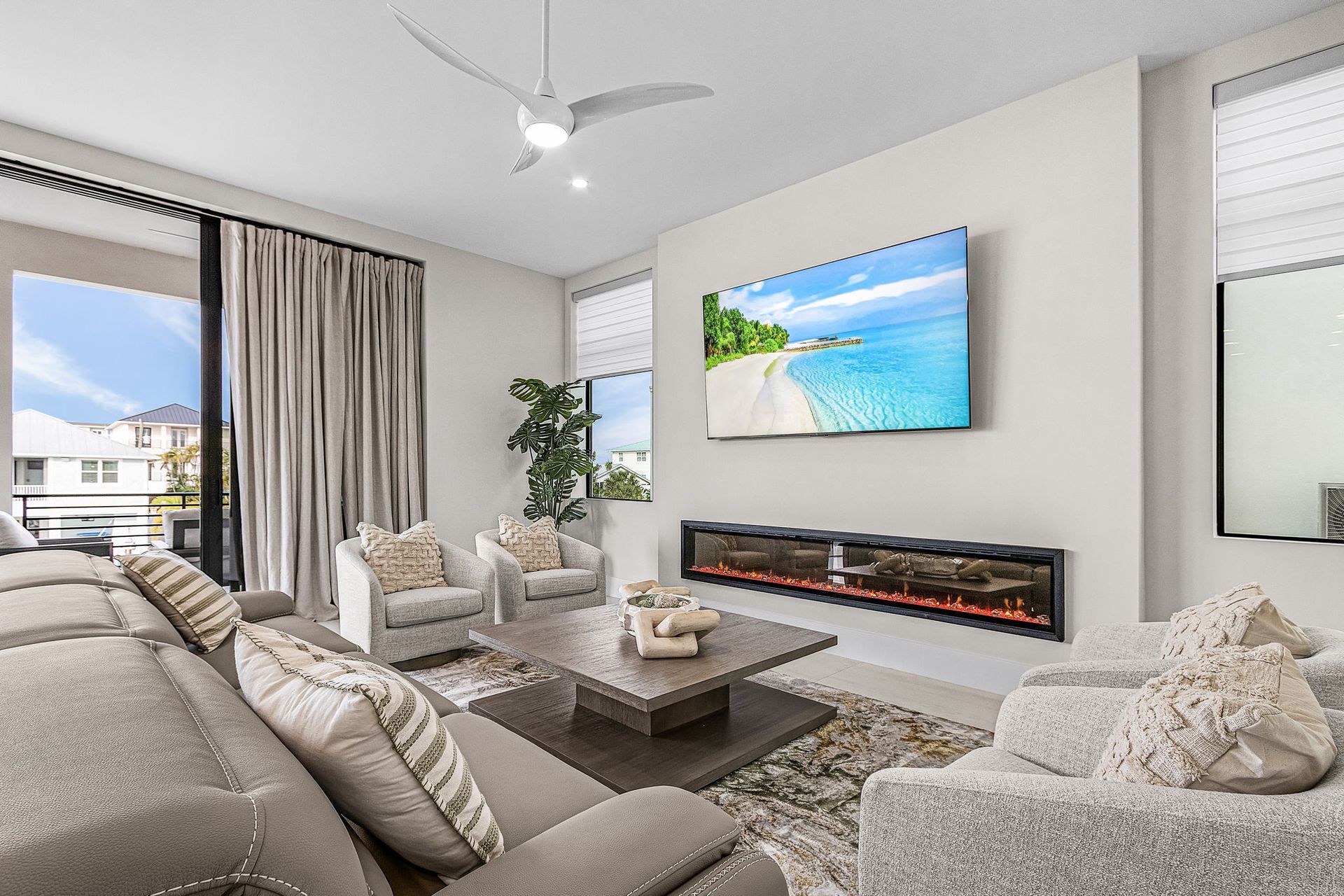 Modern living room with sectional sofa, fireplace, and TV displaying a beach scene.