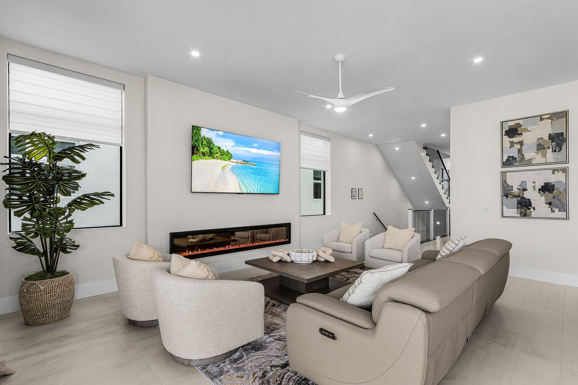 Living room with a TV over a fireplace, two armchairs, a sofa, and stairs.