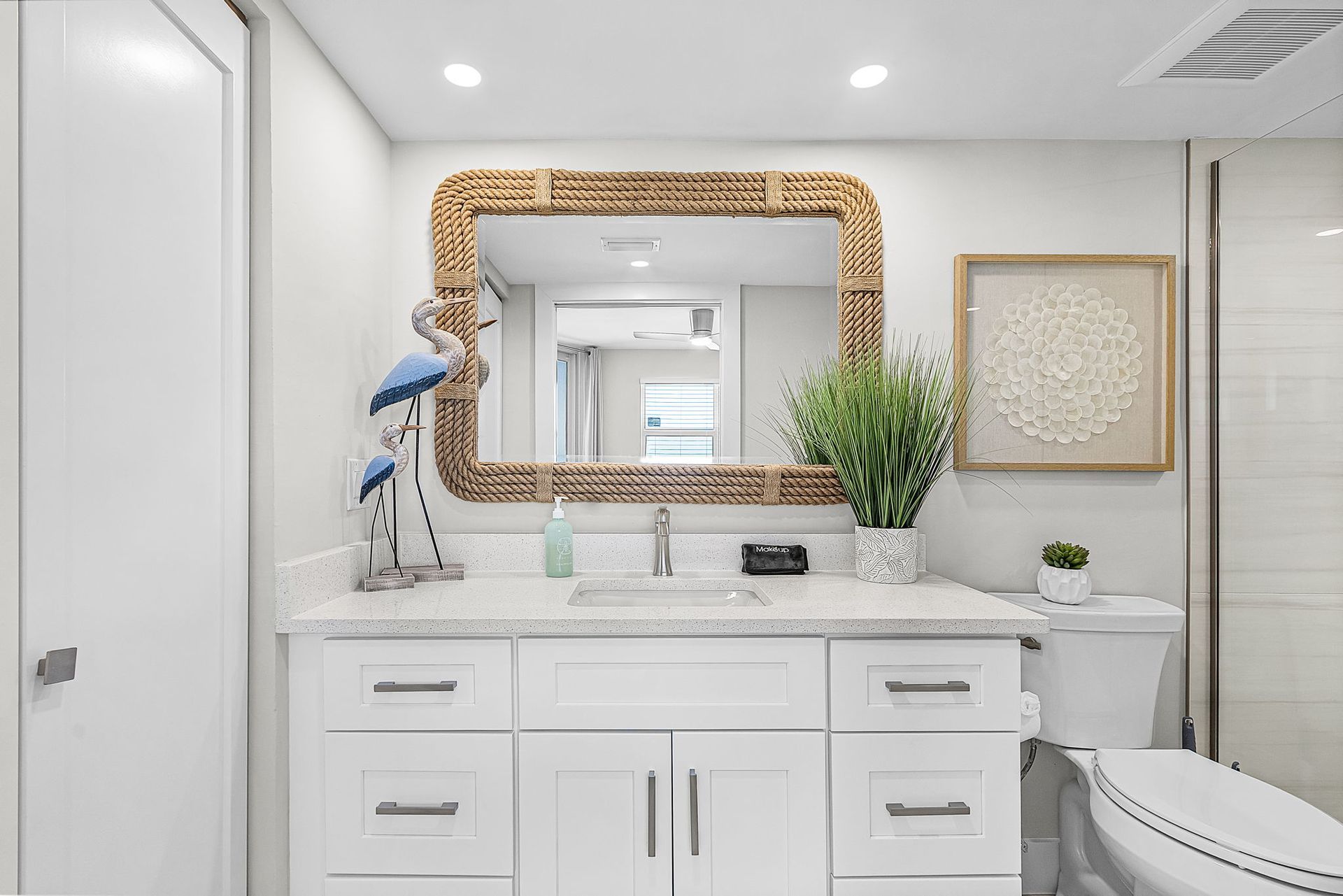 White bathroom with vanity, mirror, decor, and shower.