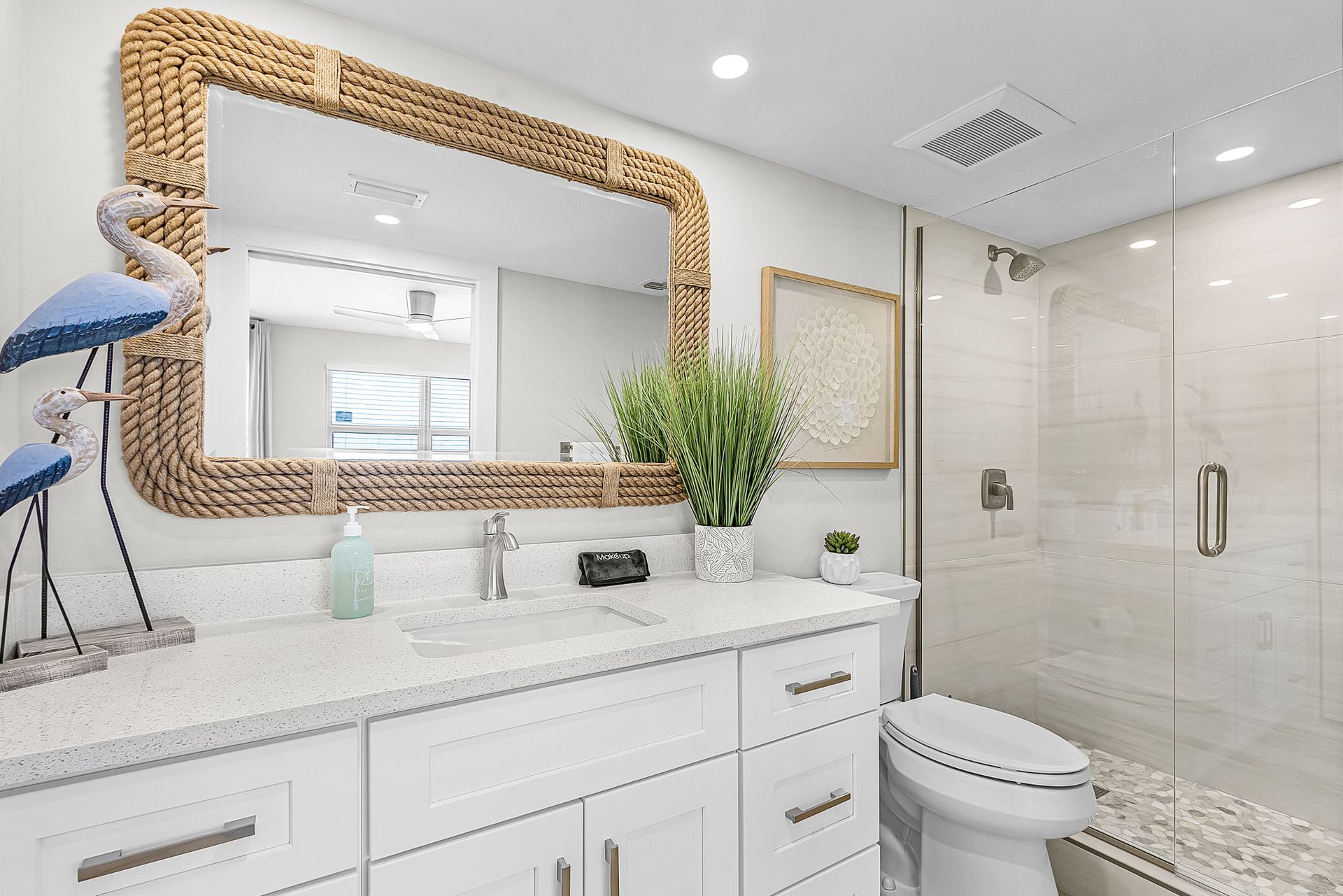 Bathroom with white vanity, large mirror, and glass shower.