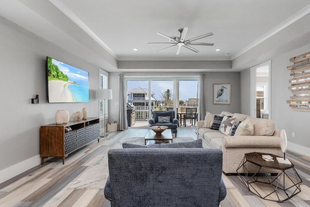 Living room with blue sofa, large TV, water view, and light wood flooring.