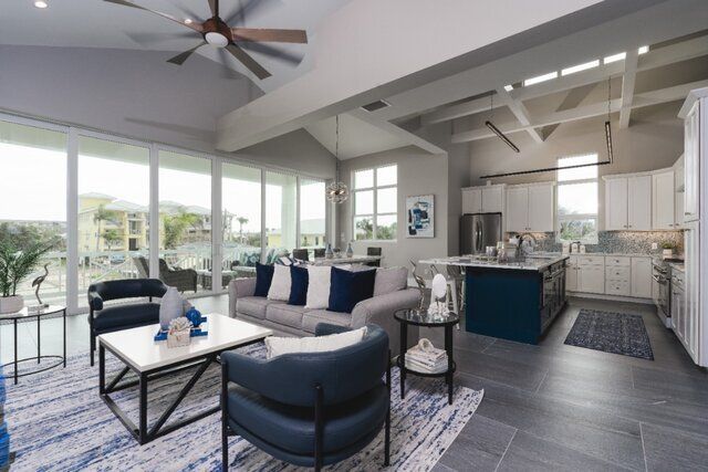 Open-concept living space with a grey sofa, blue chairs, and a kitchen with a blue island.