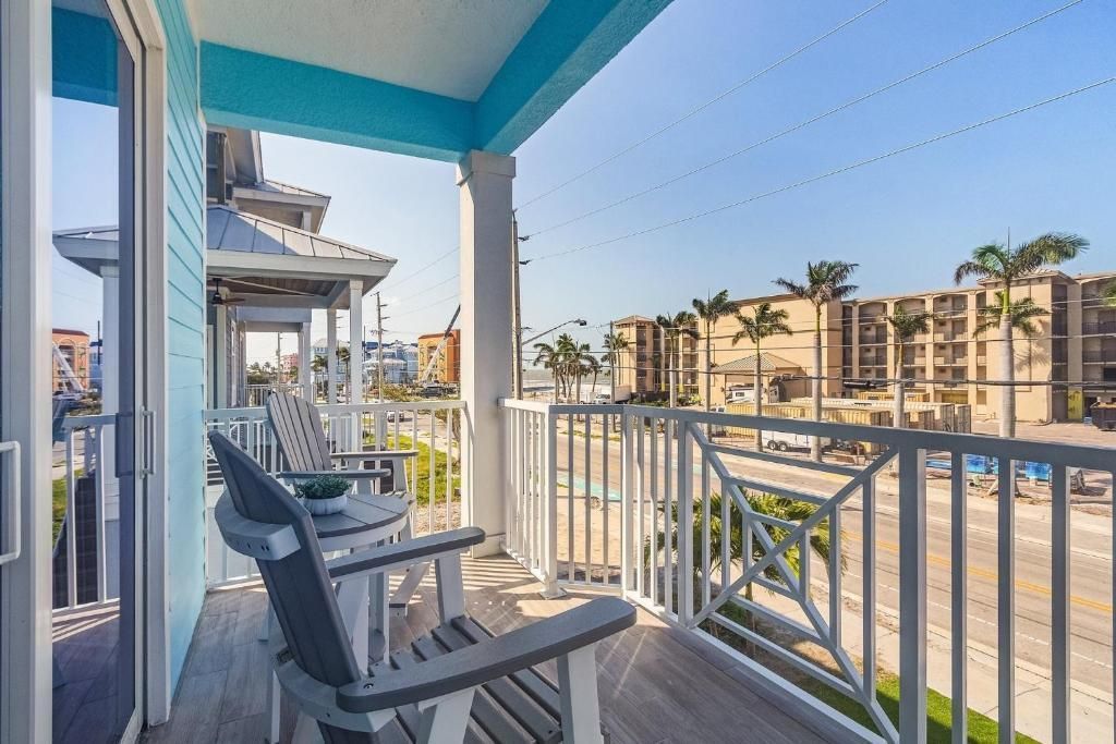 Balcony with two chairs overlooking a street and buildings; blue and white exterior.