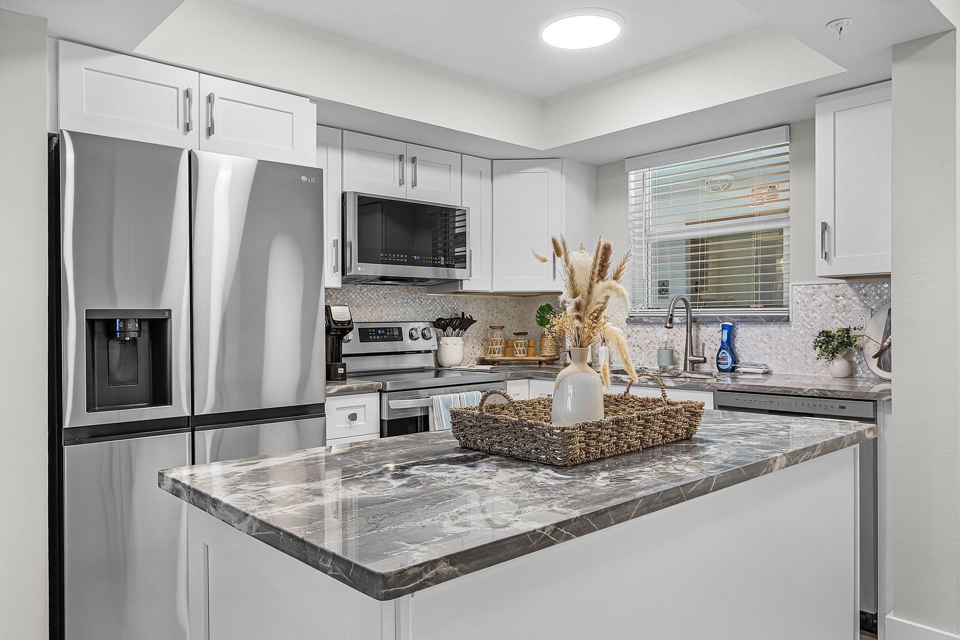 Modern white kitchen with stainless steel appliances and a center island.