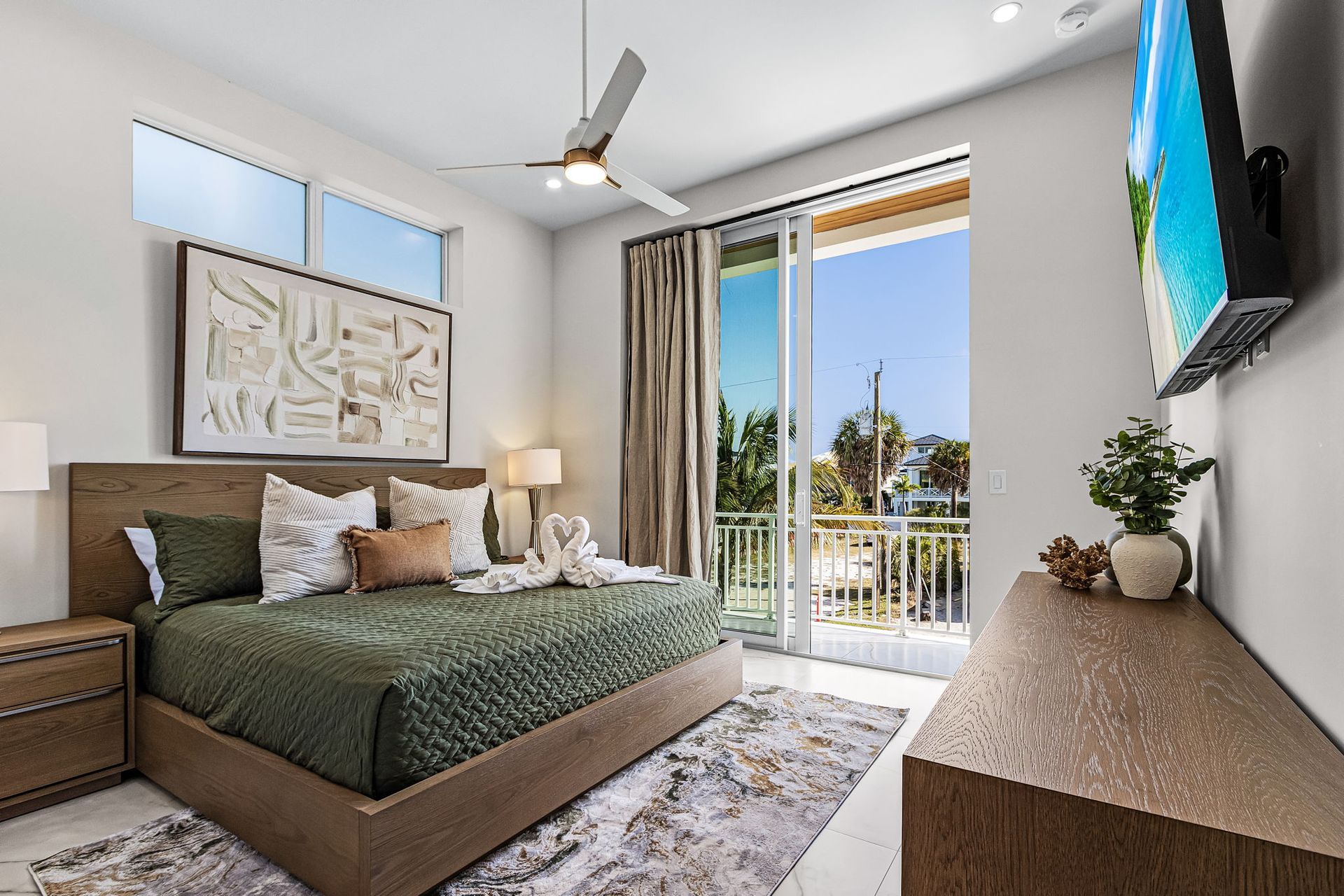 Bedroom with green bed, wooden furniture, and balcony view.
