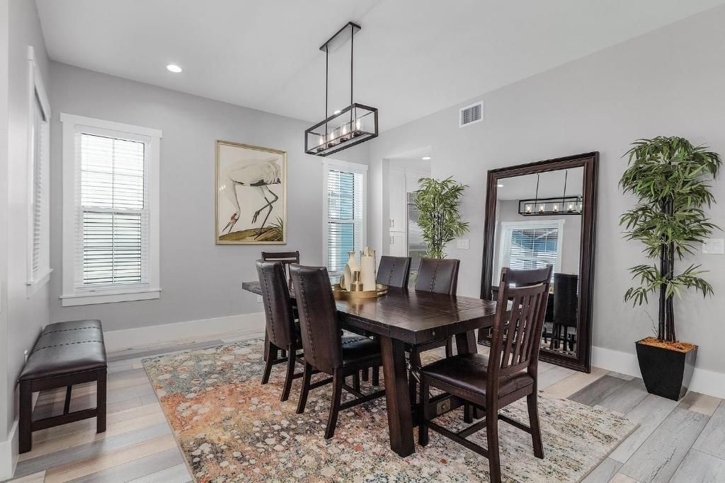 Dining room with dark wood table, chairs, large mirror, rug, and greenery.
