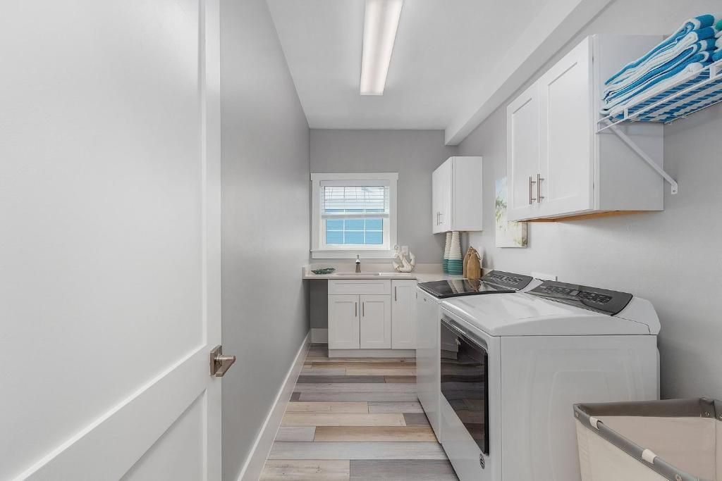 Laundry room with a washing machine, cabinets, and a window.
