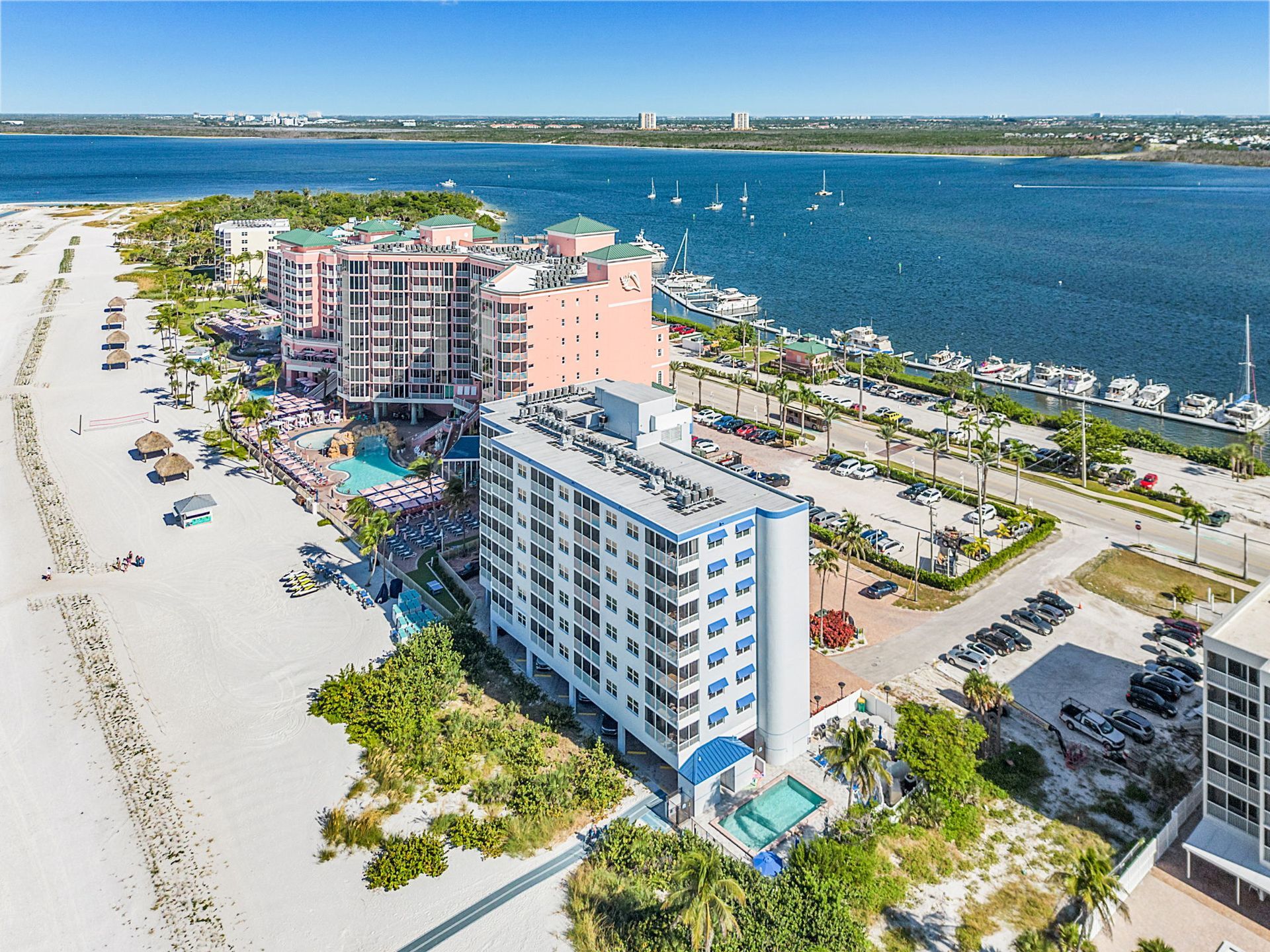 Beachfront buildings and marina by the ocean under a clear sky.