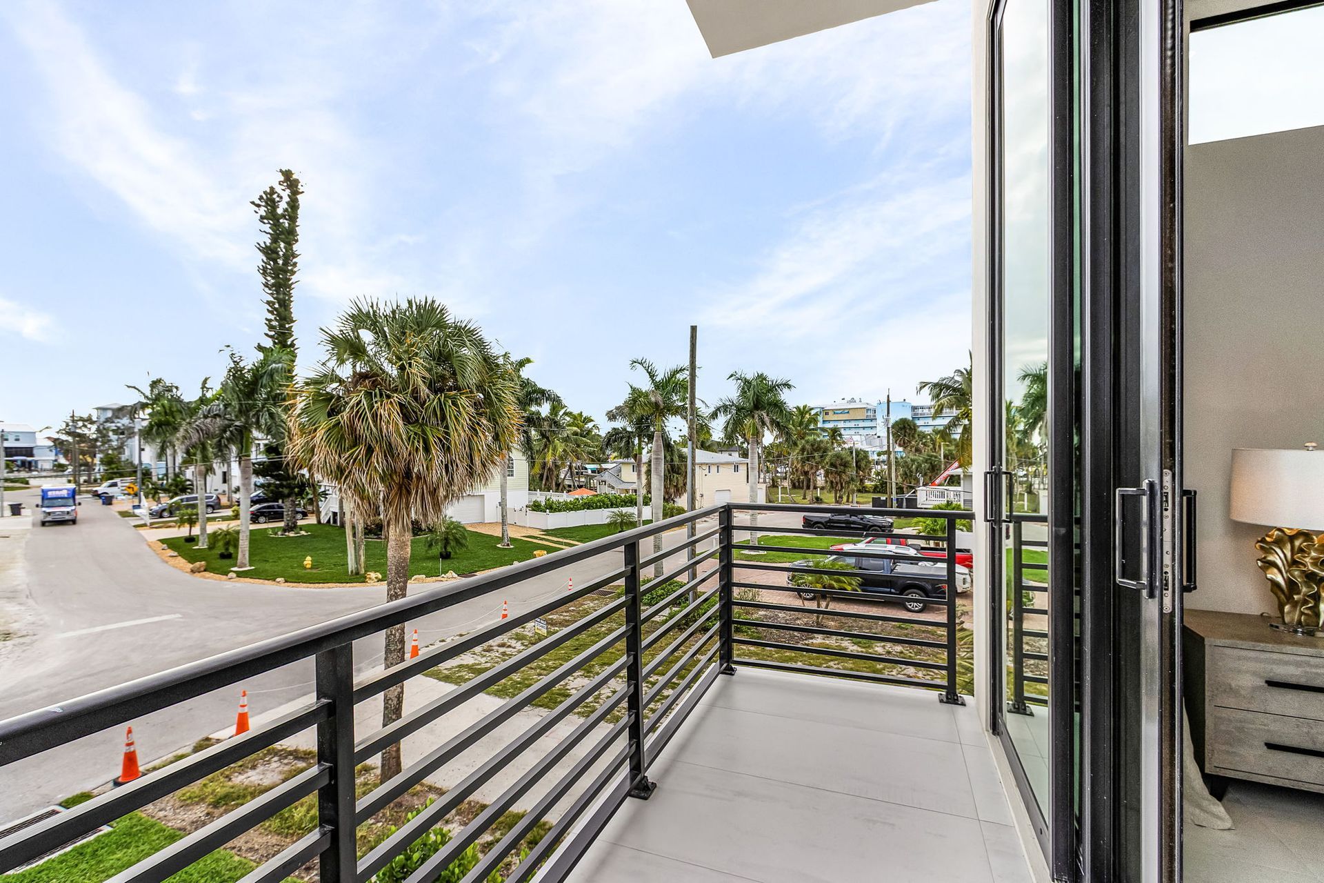 Balcony overlooking a street lined with palm trees. A glass sliding door leads inside.