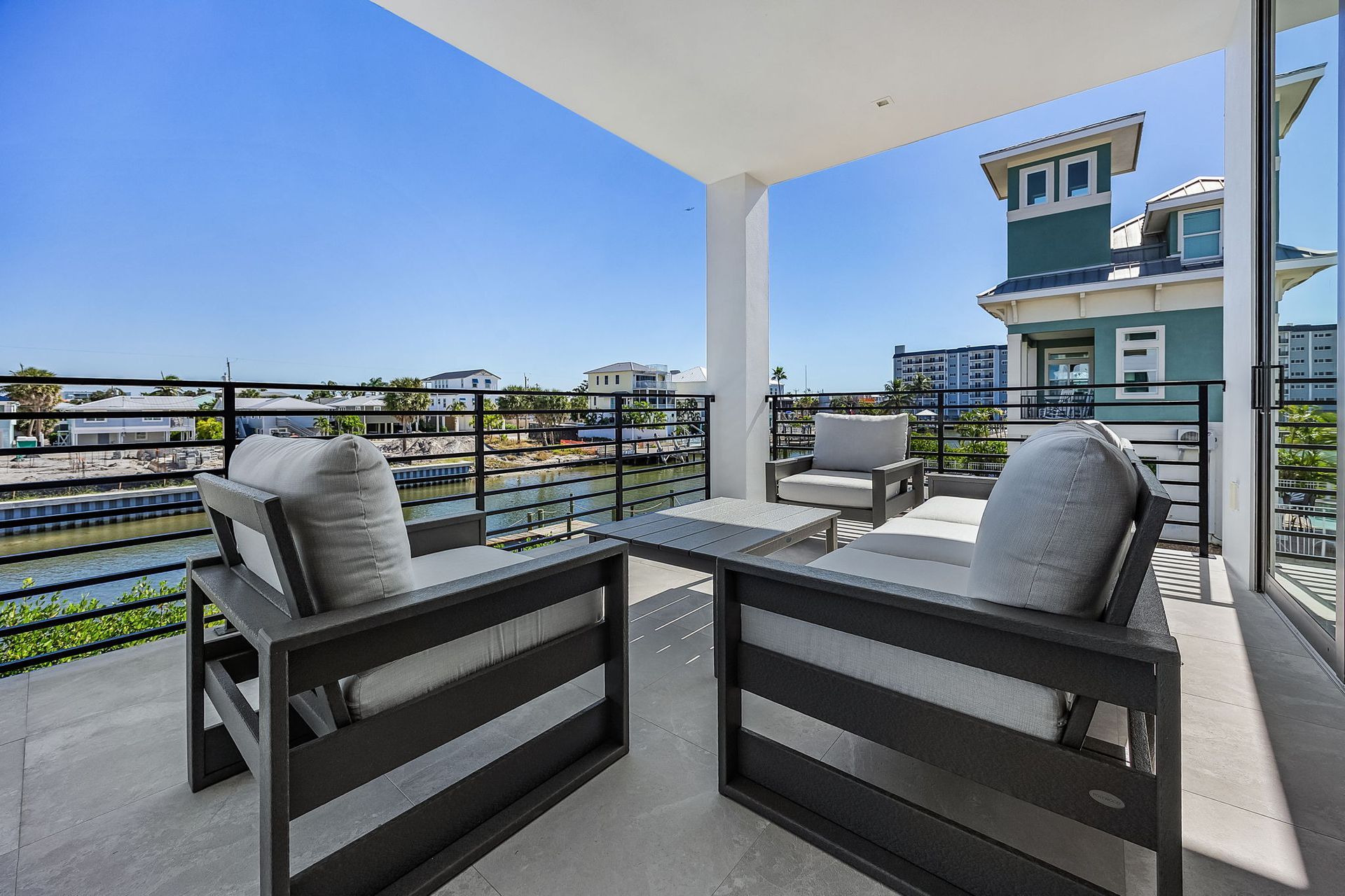 Balcony with modern outdoor furniture, overlooking a waterway.
