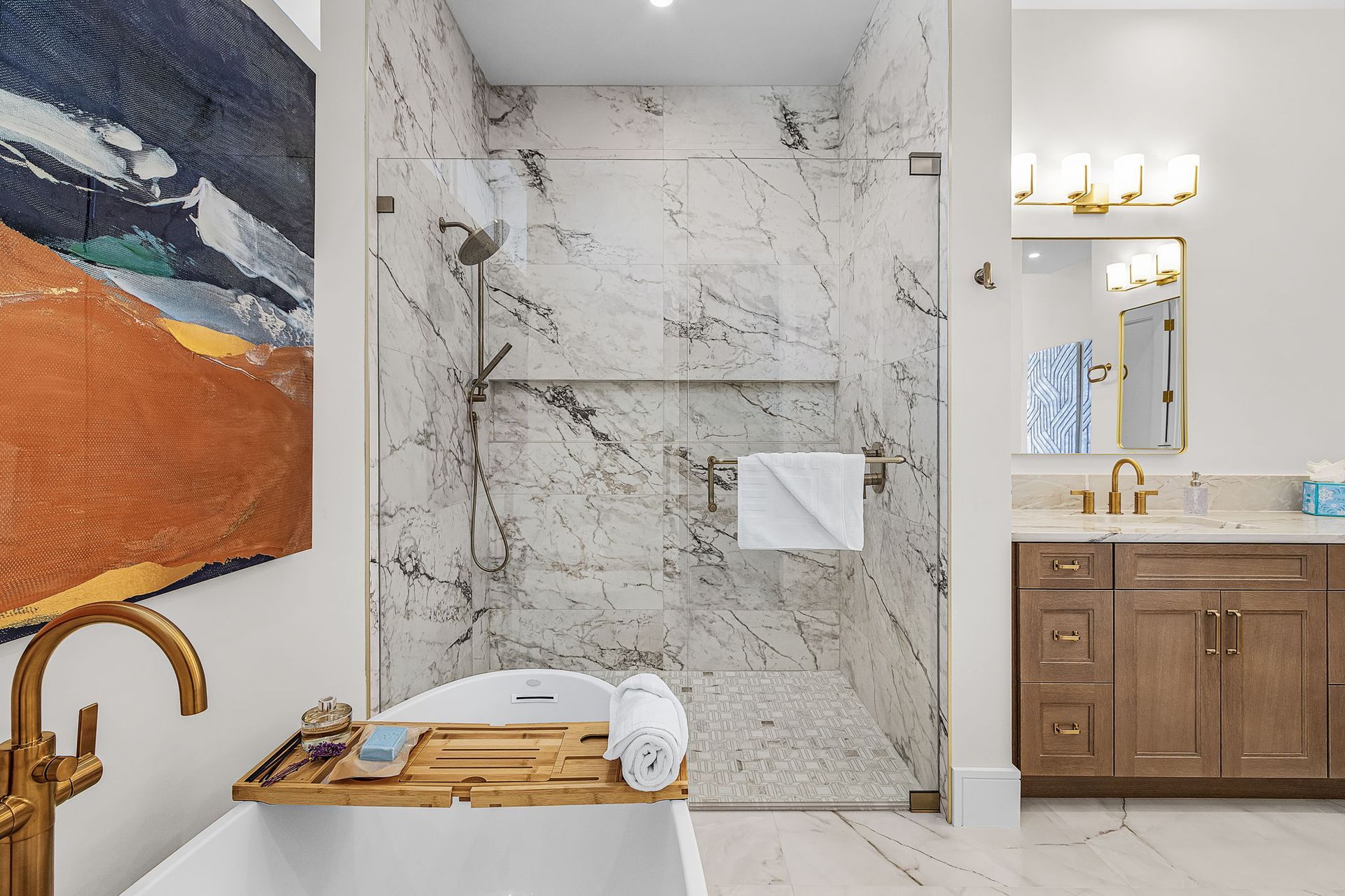 Bathroom with marble shower, vanity with gold fixtures, and a freestanding tub.