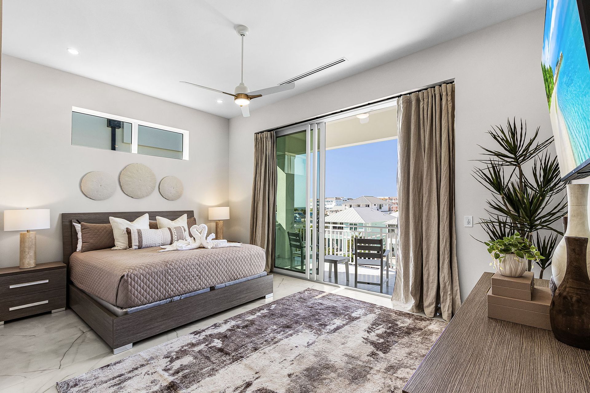 Bedroom with bed, rug, sliding glass door to balcony, neutral tones.
