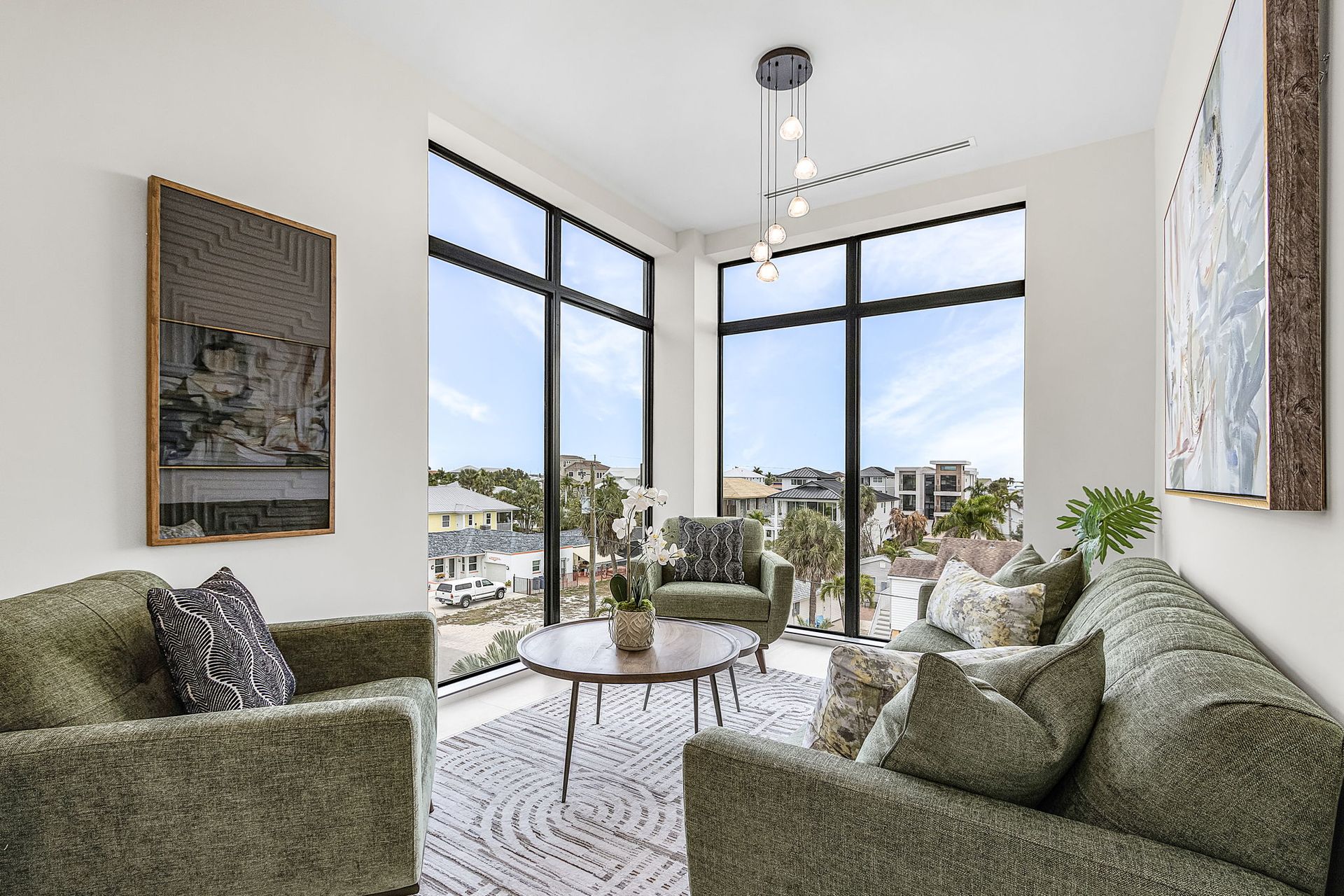 Living room with green furniture, large windows, and city view.