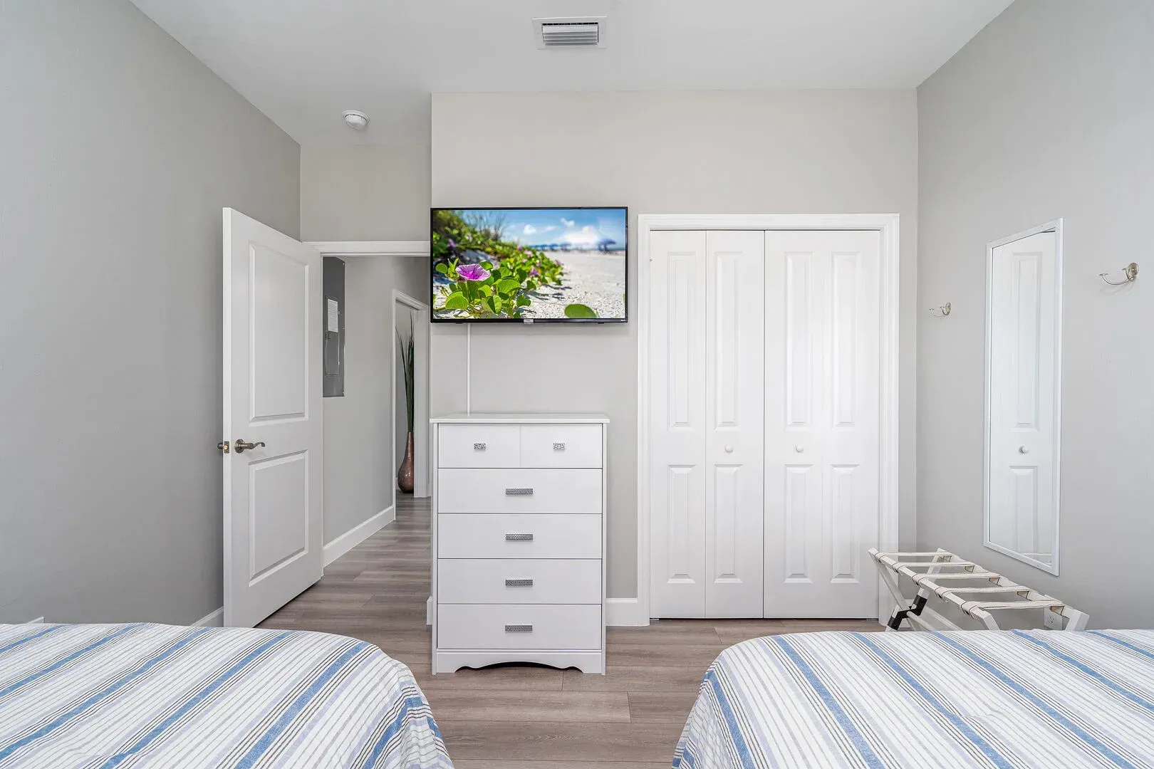 Bedroom with two twin beds, TV, dresser, closet, and a hallway door.