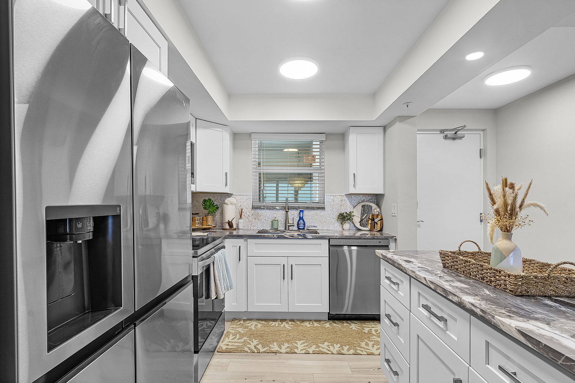 Modern kitchen with stainless steel appliances, white cabinets, and a gray countertop island.