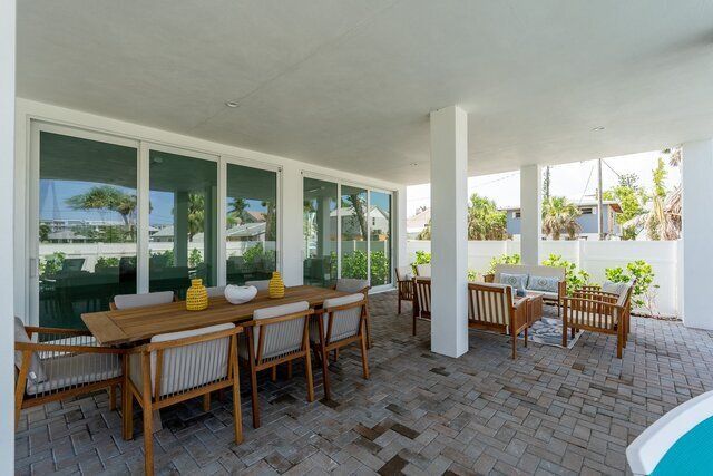 Covered patio with dining table and seating, overlooking greenery.