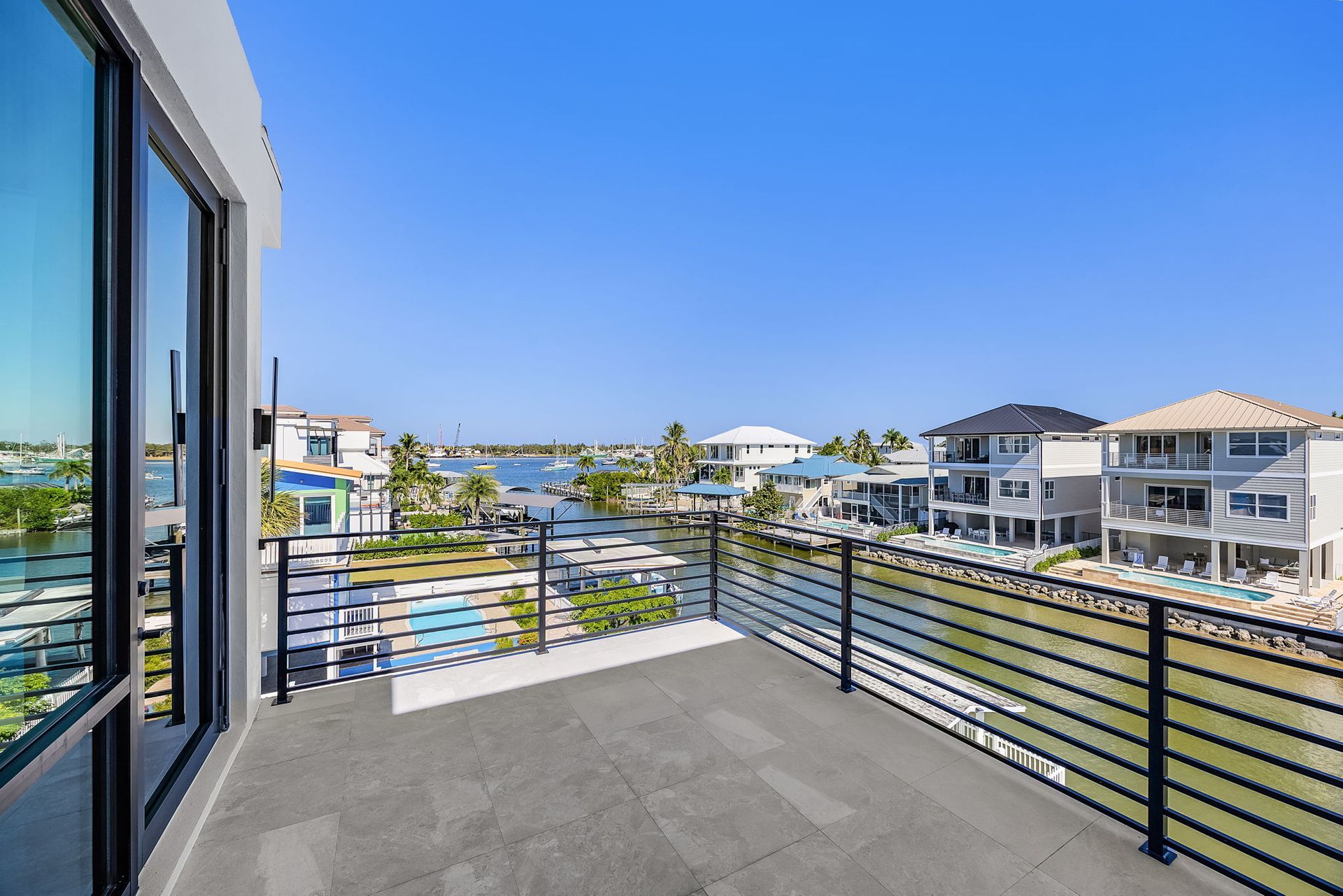 Balcony overlooking a waterway with houses, blue sky.
