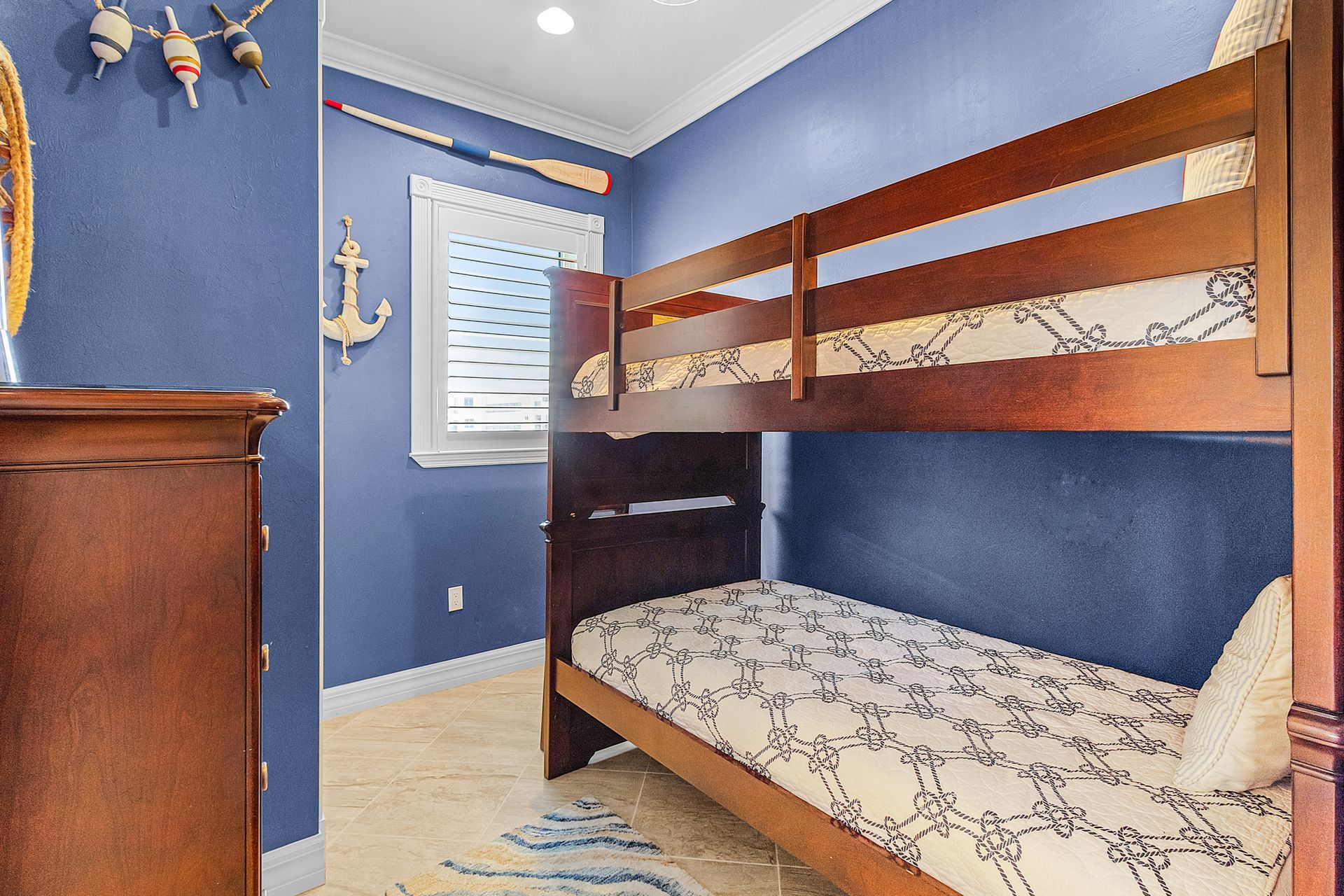 Blue bedroom with wooden bunk beds, a window, and a dresser