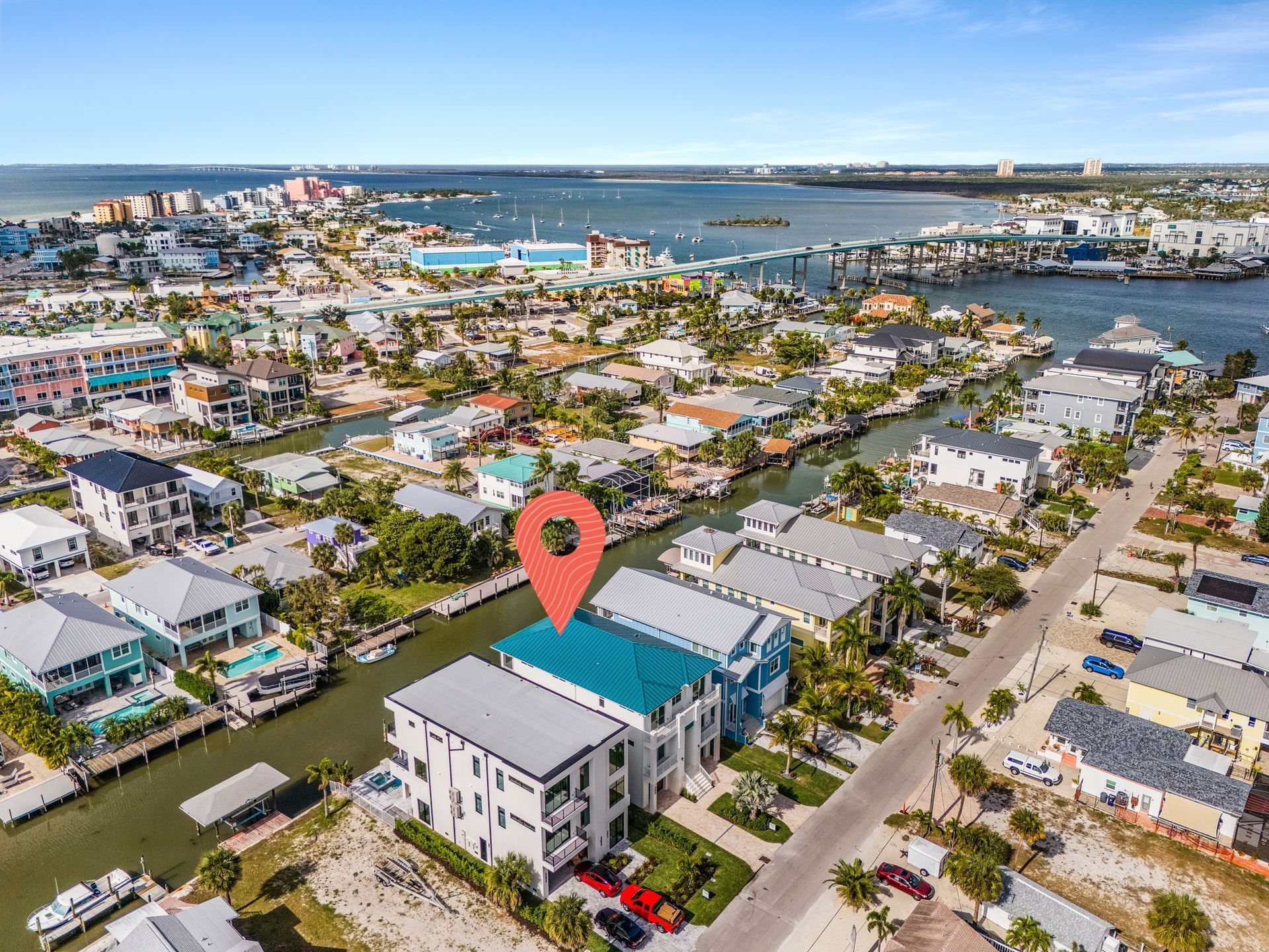 Aerial view of waterfront houses and canals, red marker pinpoints a turquoise-roofed building.