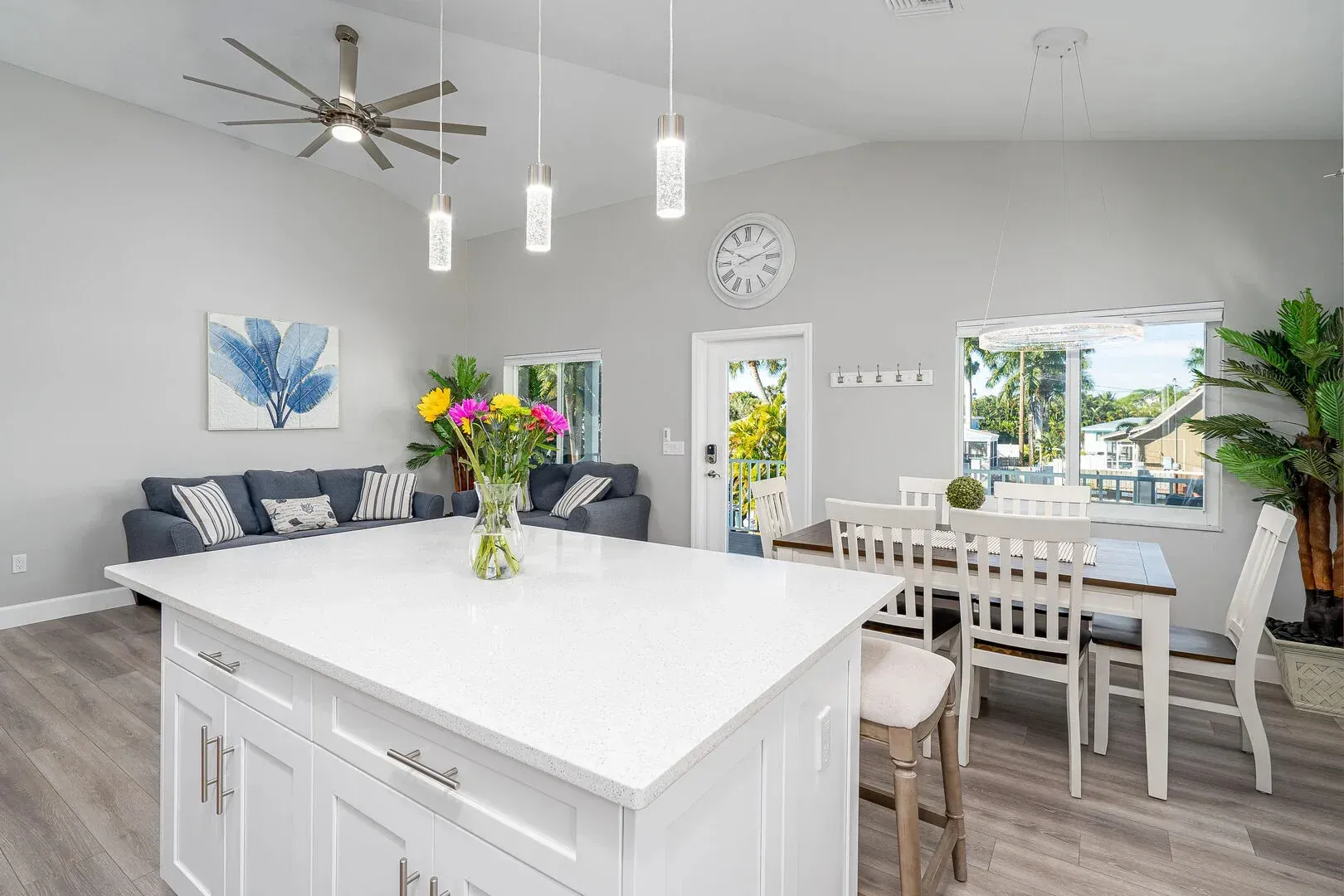Modern open-concept living space with white kitchen island, dining area, and gray sofa.