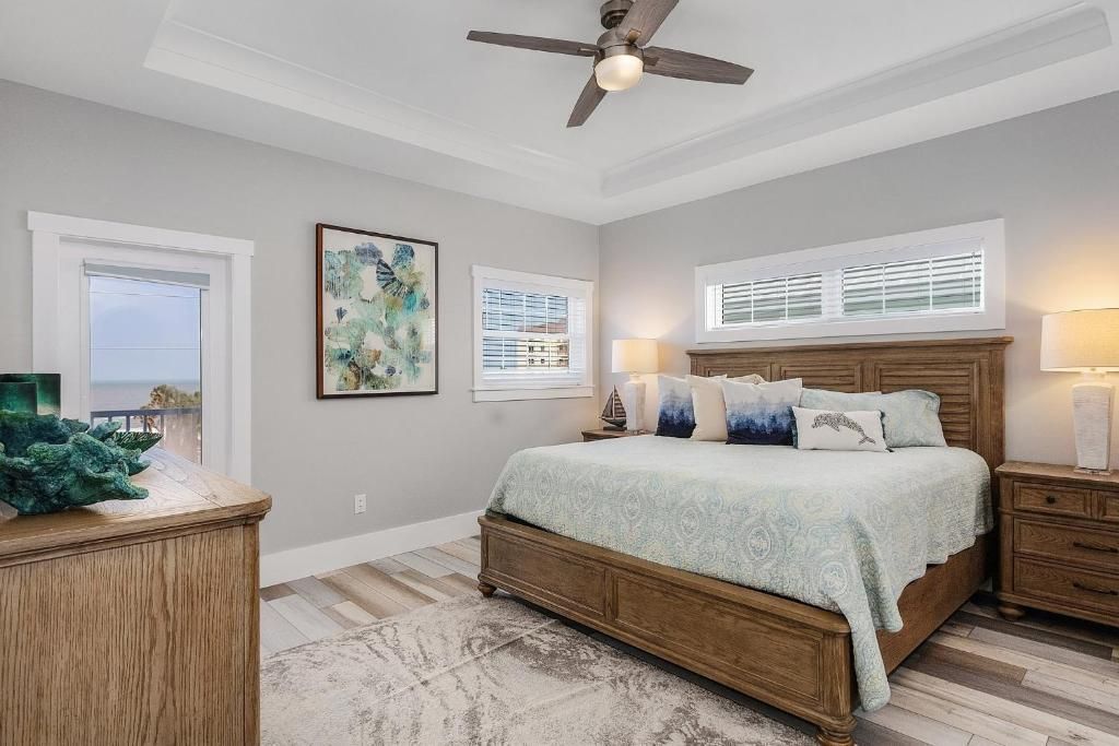 Bedroom with light gray walls, wooden furniture, and ocean view from windows.