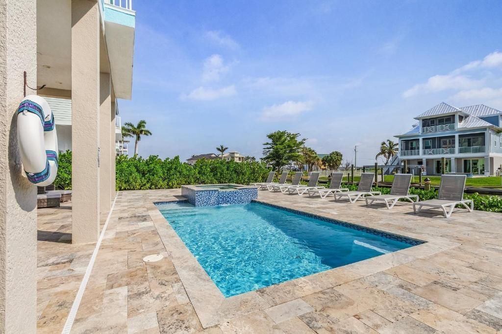 Swimming pool and lounge chairs near a building with a blue sky background.