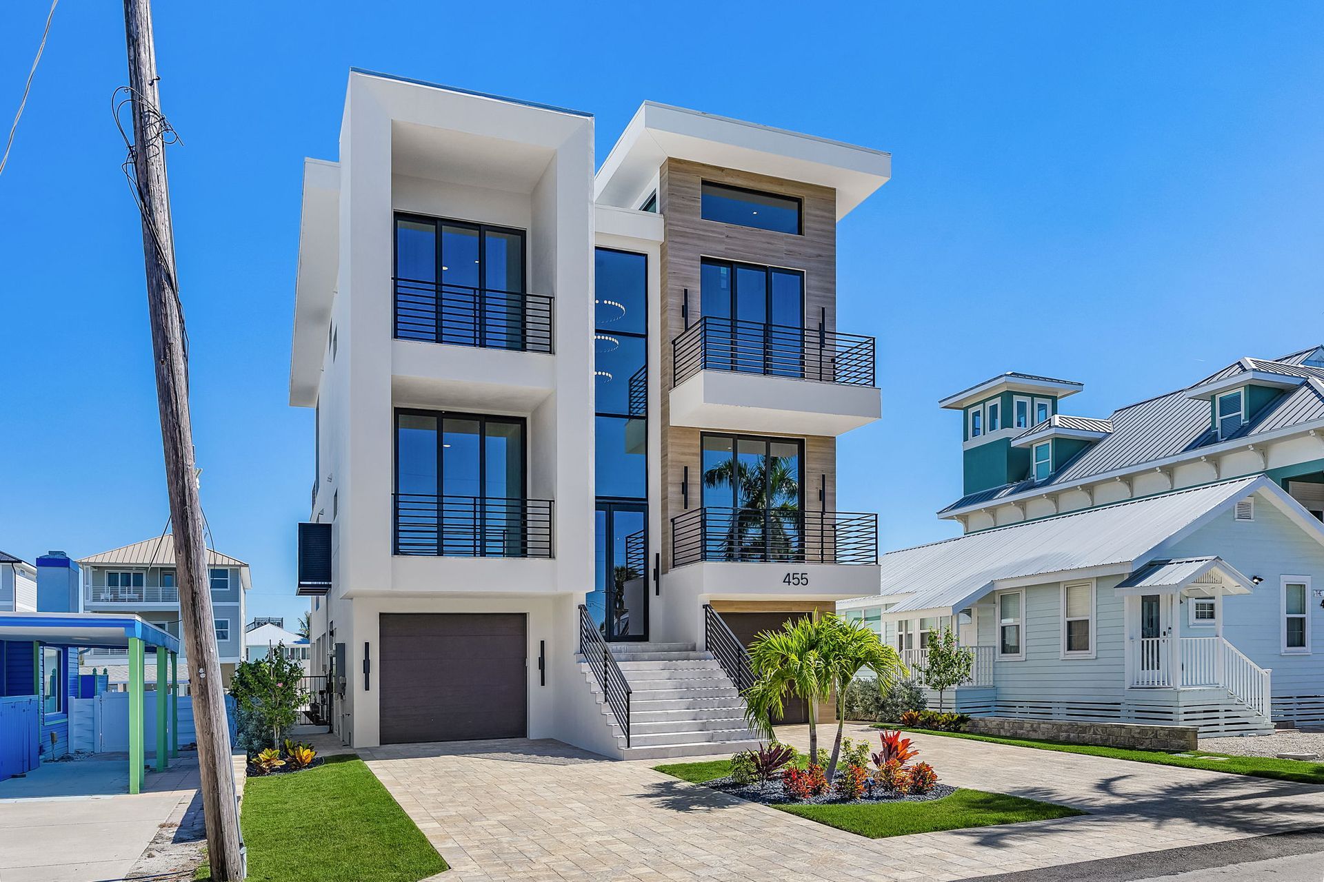 Modern three-story house with a white exterior, large windows, and a brown garage door.