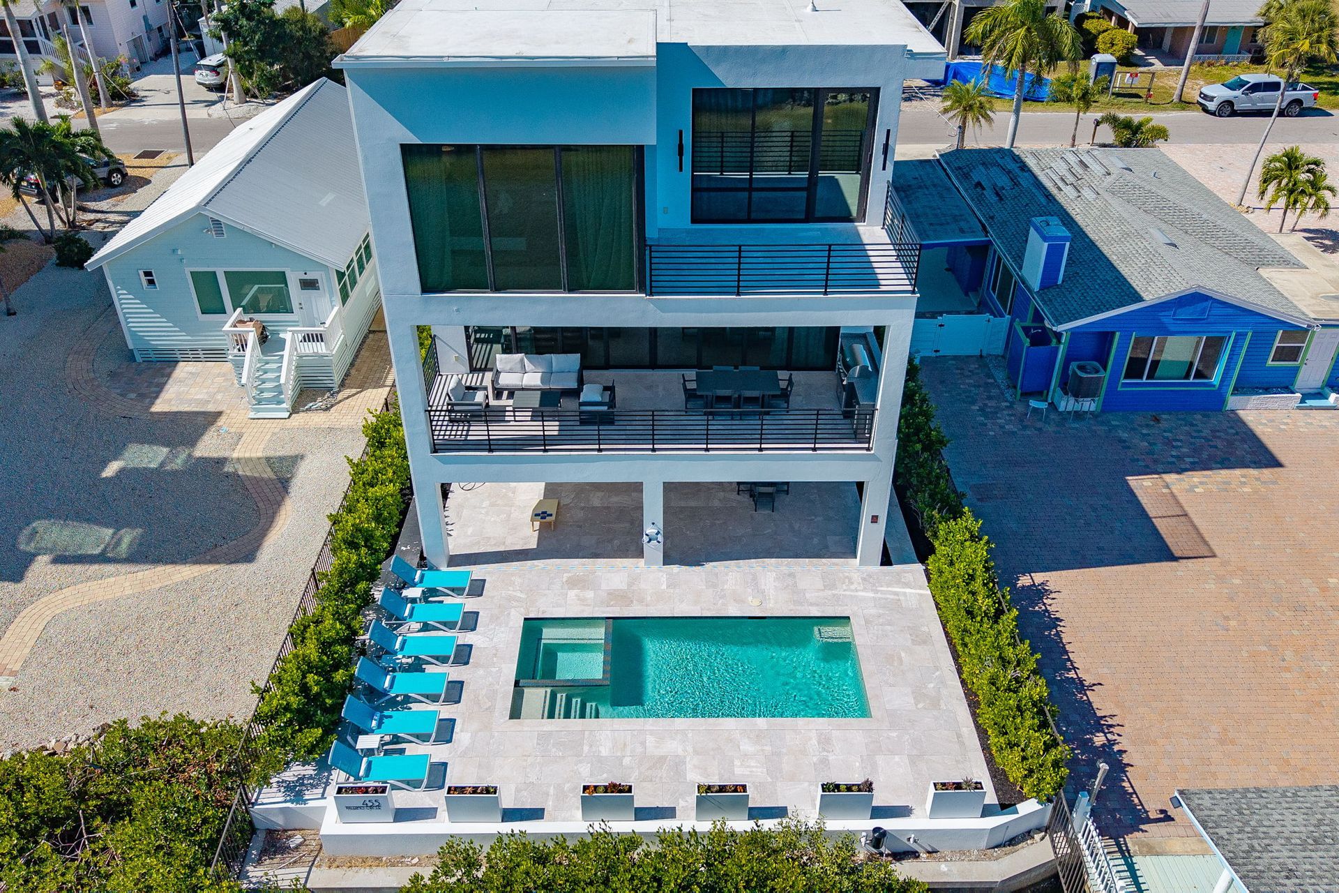 Modern two-story house with a pool. White exterior, black window frames, and blue pool loungers.